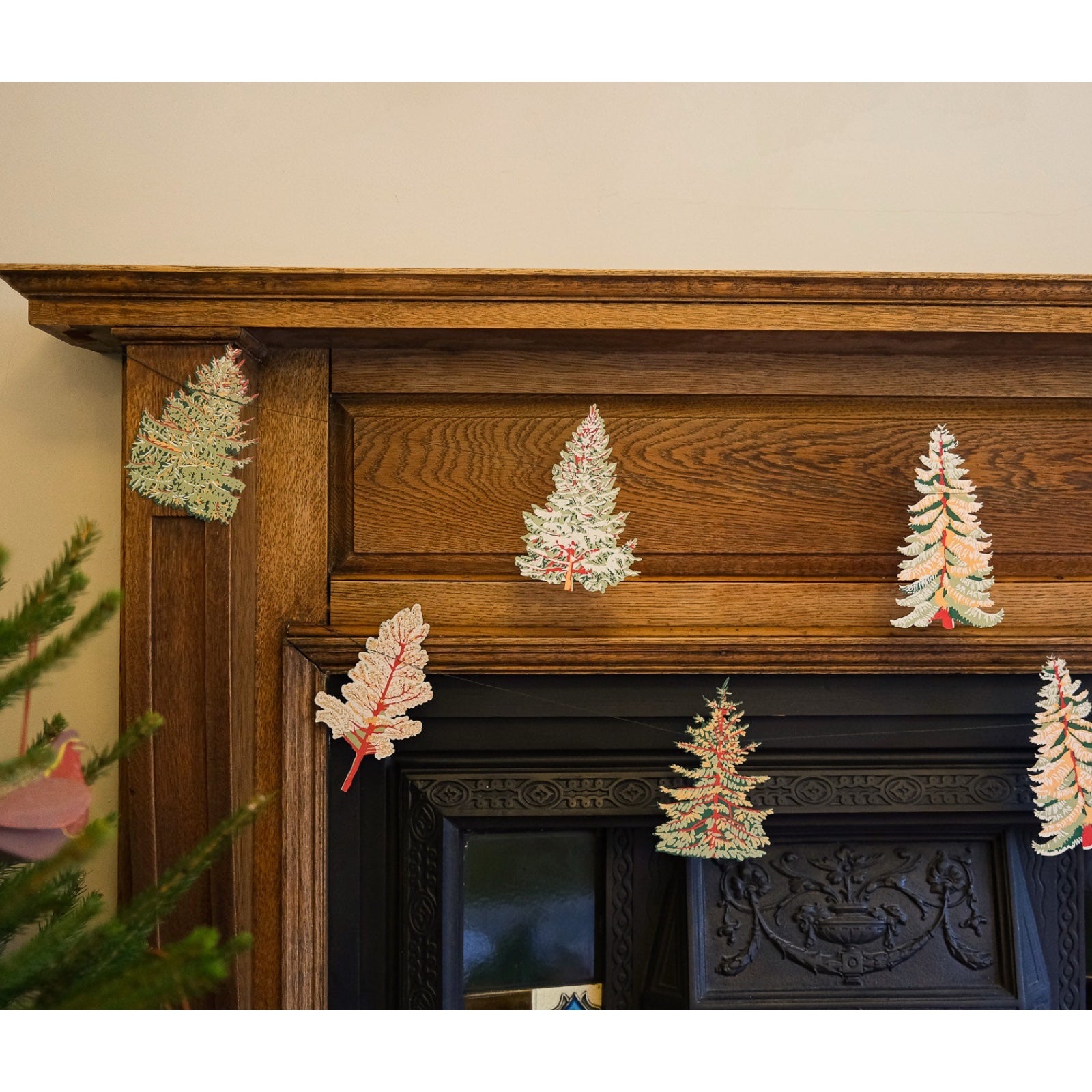 Forest paper garland, featuring ten screen-printed trees hanging along a wooden fireplace.