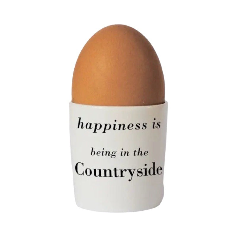 Bone china egg cup with the text 'happiness is being in the countryside' written in black on the back.