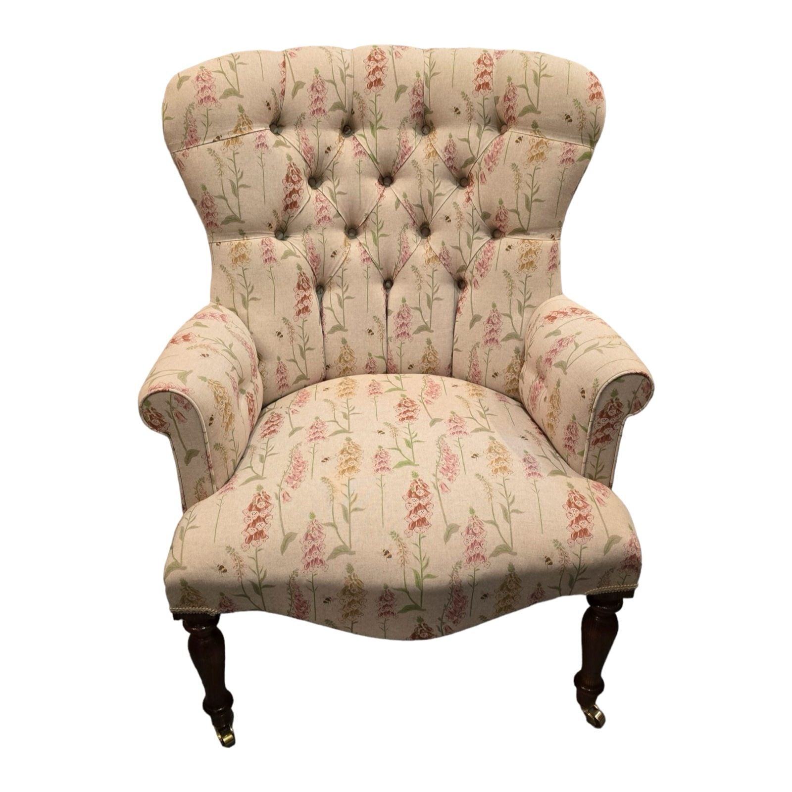 A hand-crafted armchair in cream linen fabric with mustard, orange and pink foxgloves and small flying bees.