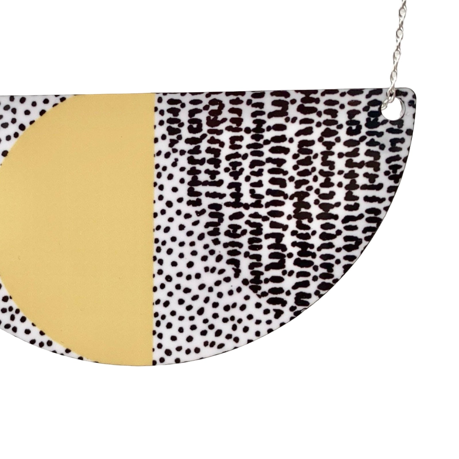 Semi-circular necklace with gold and black and white patterned sections on a white background.