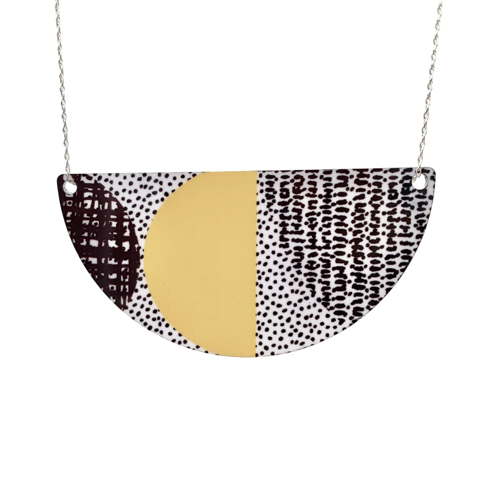 Semi-circular pendant with gold center and black and white patterned edges on a white background.