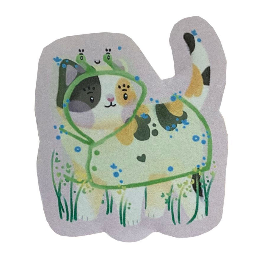 Photo of a sticker of a calico cat wearing a frog raincoat