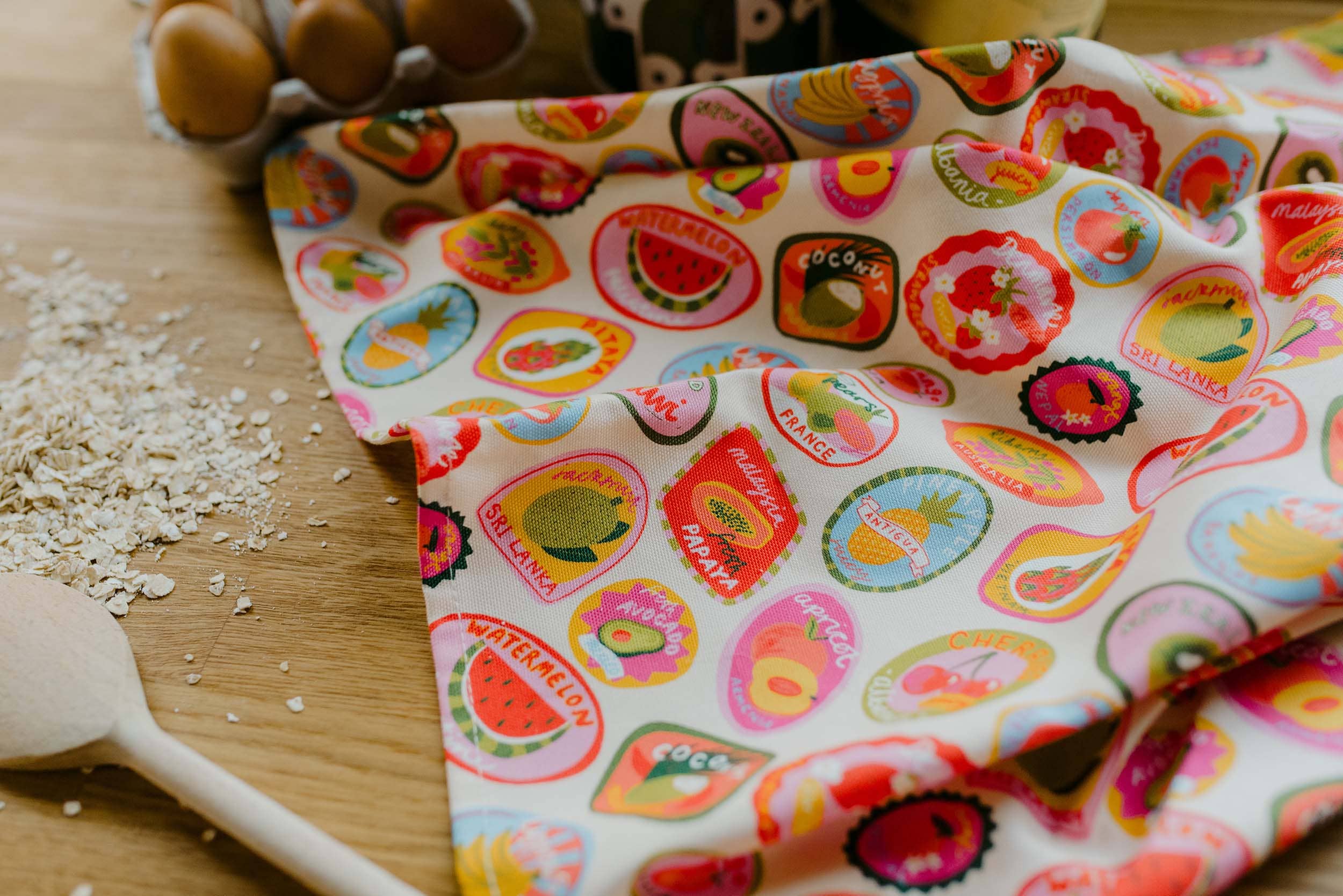 Fabric with colourful fruit pattern on a wooden surface.