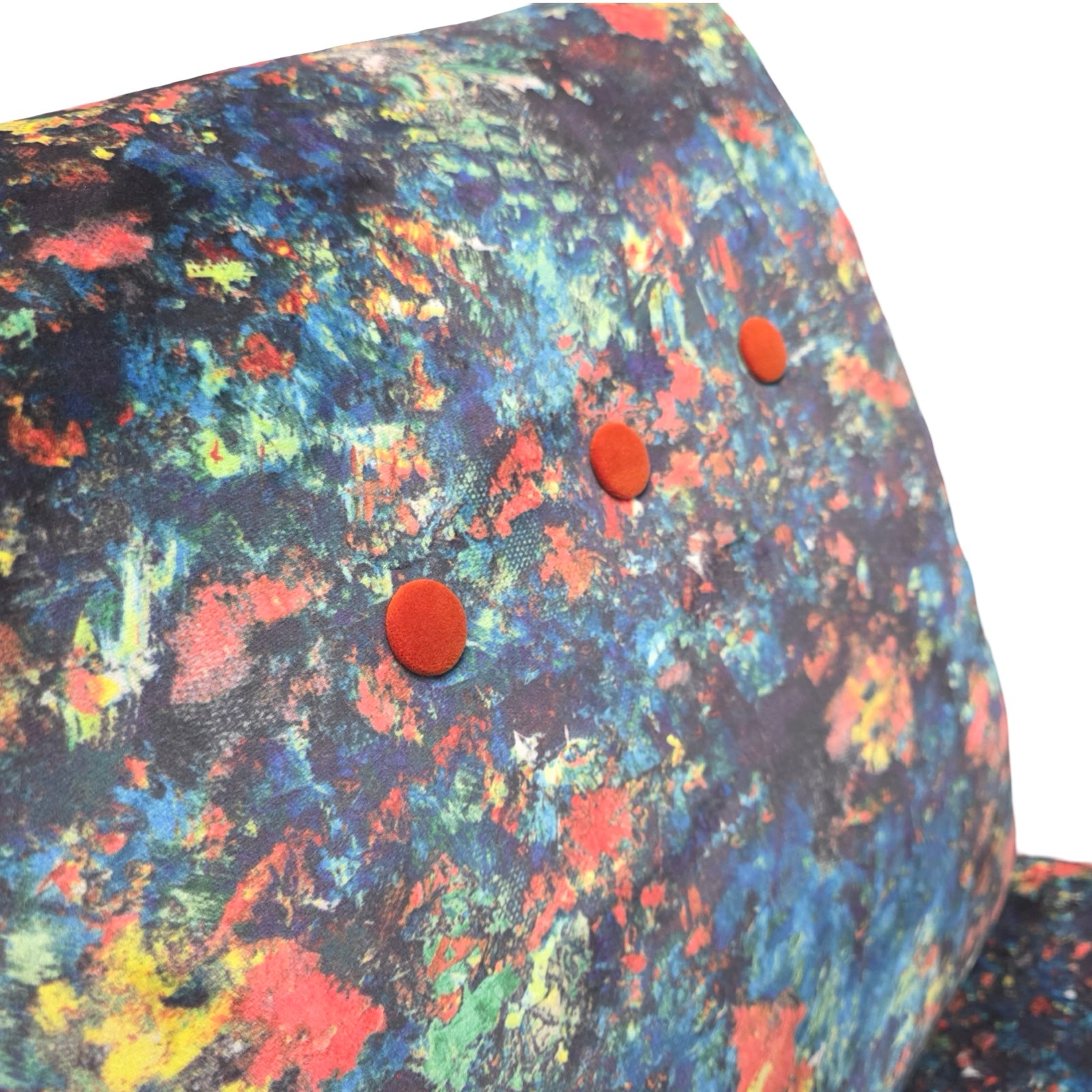 Colorful abstract patterned fabric chair with red buttons on a white background.