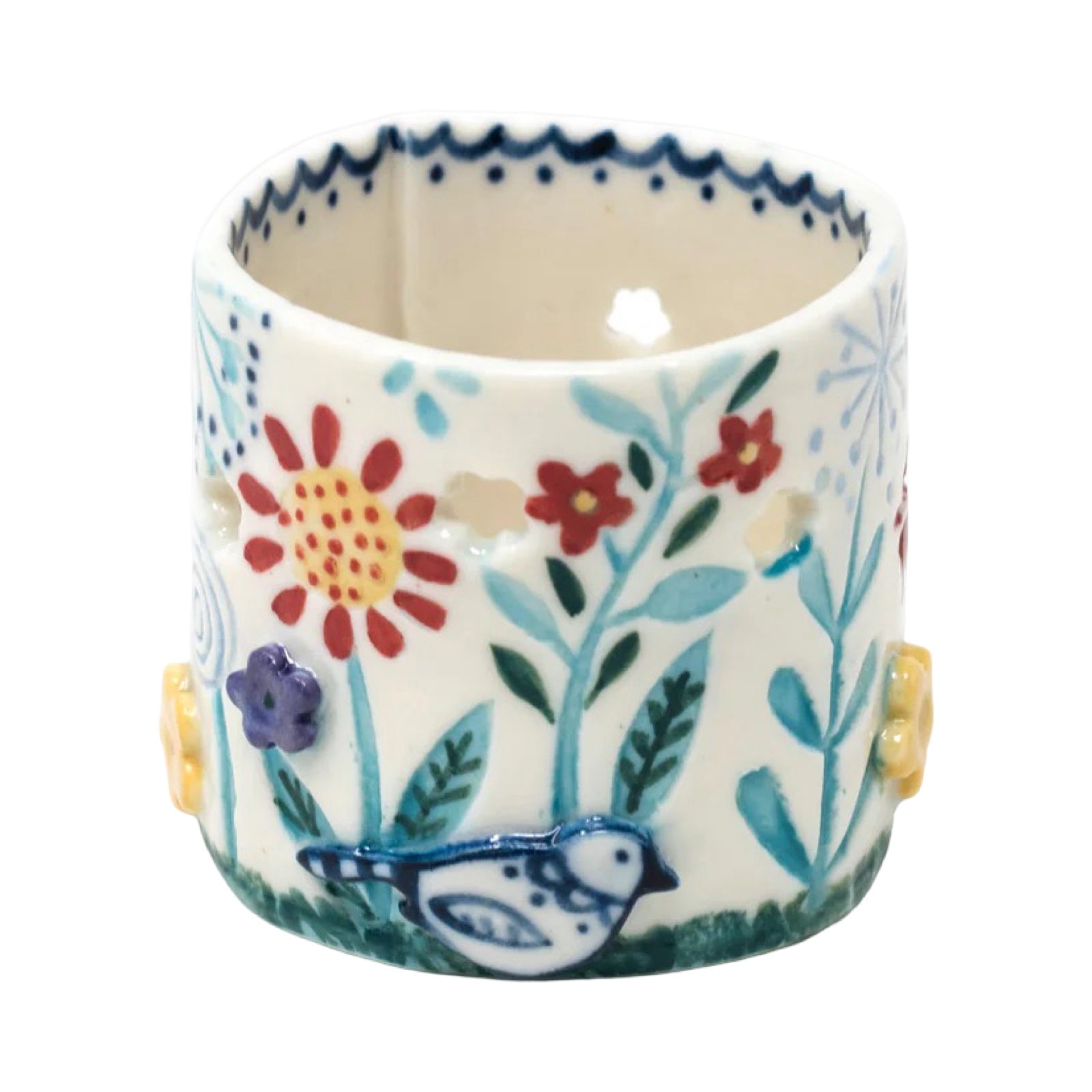 This handmade porcelain tea light holder features two beautiful blue and white birds sitting in a green tree, a small house and a second tree.