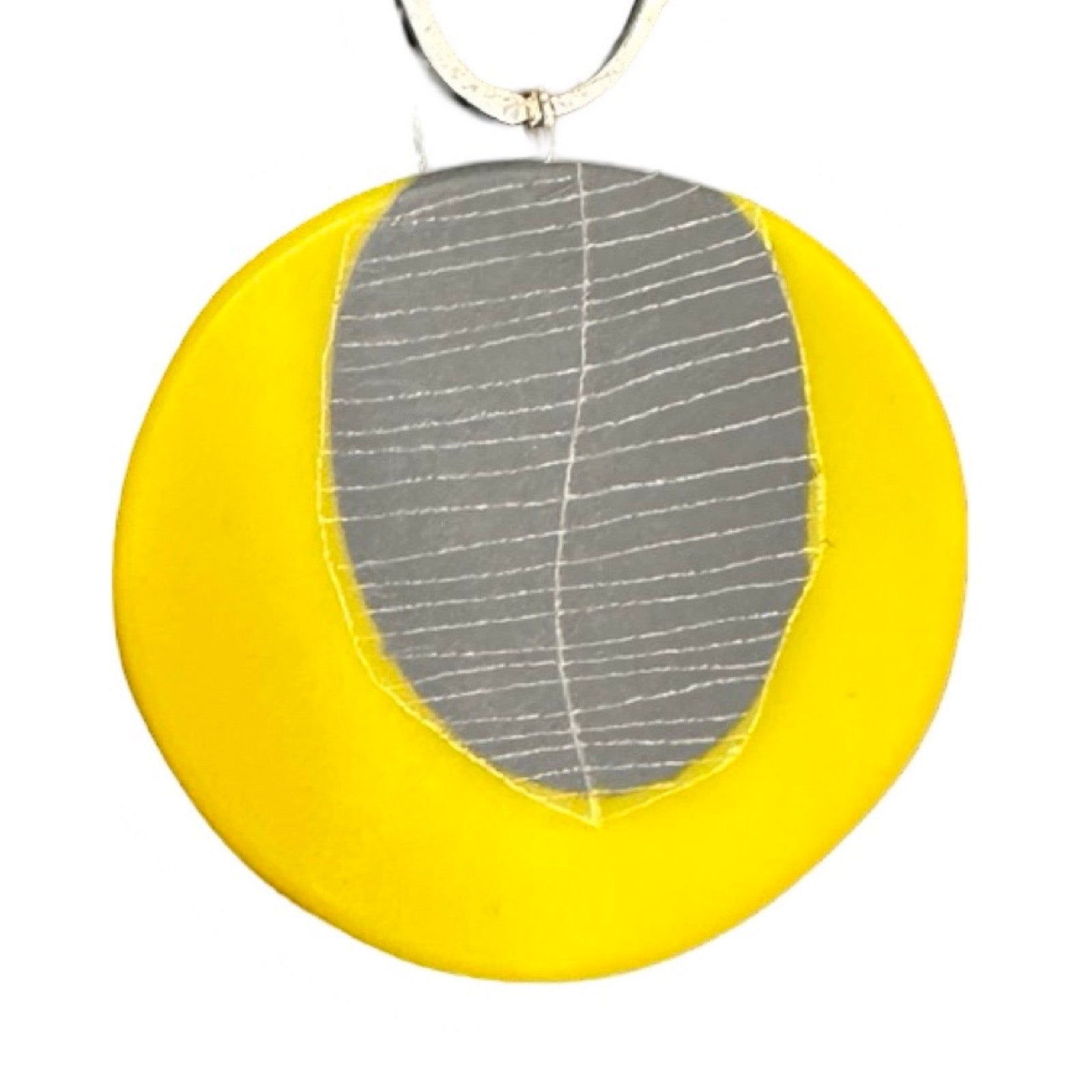 Close up of yellow pendant with grey leaf design.