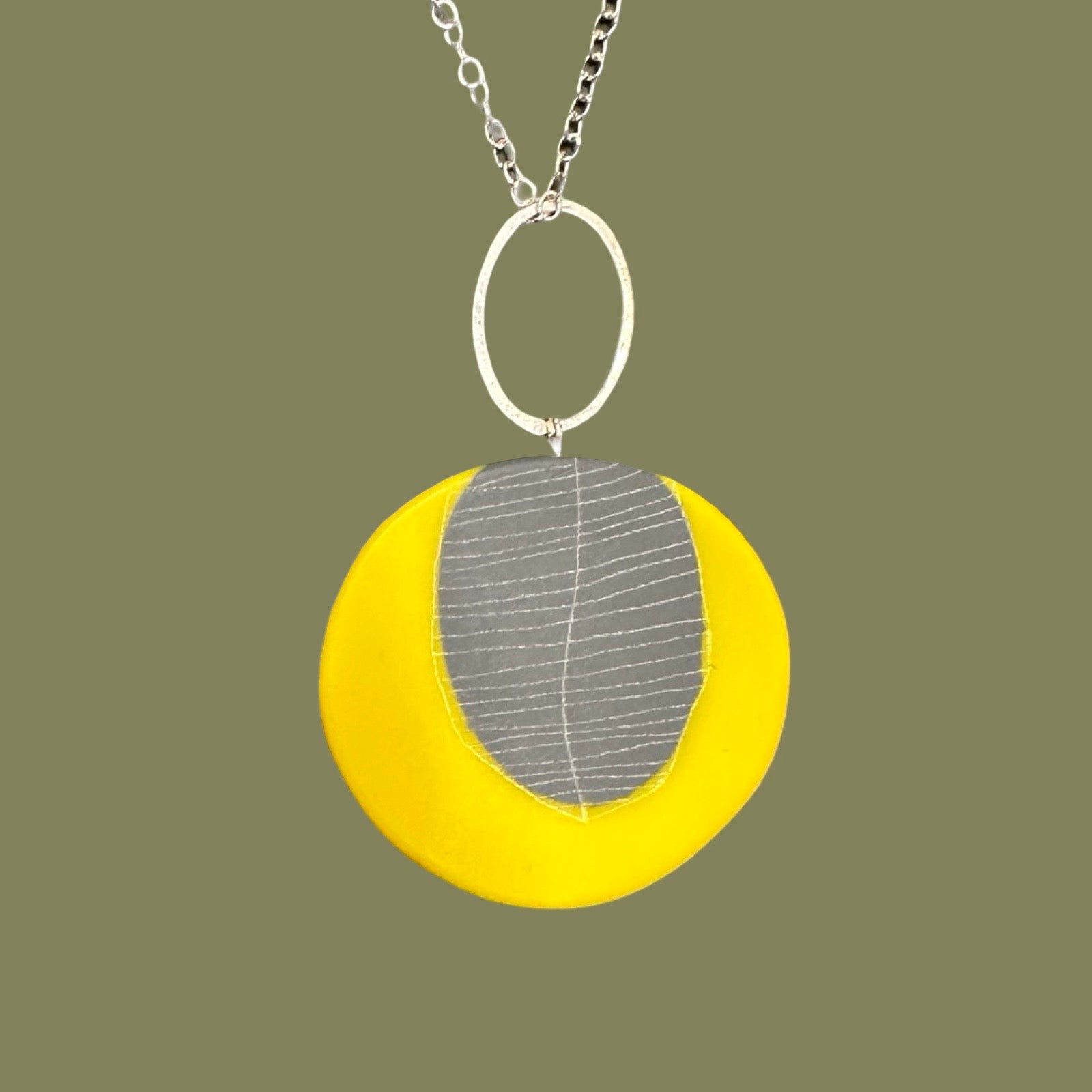 Necklace with a yellow pendant featuring a leaf design on a green background.