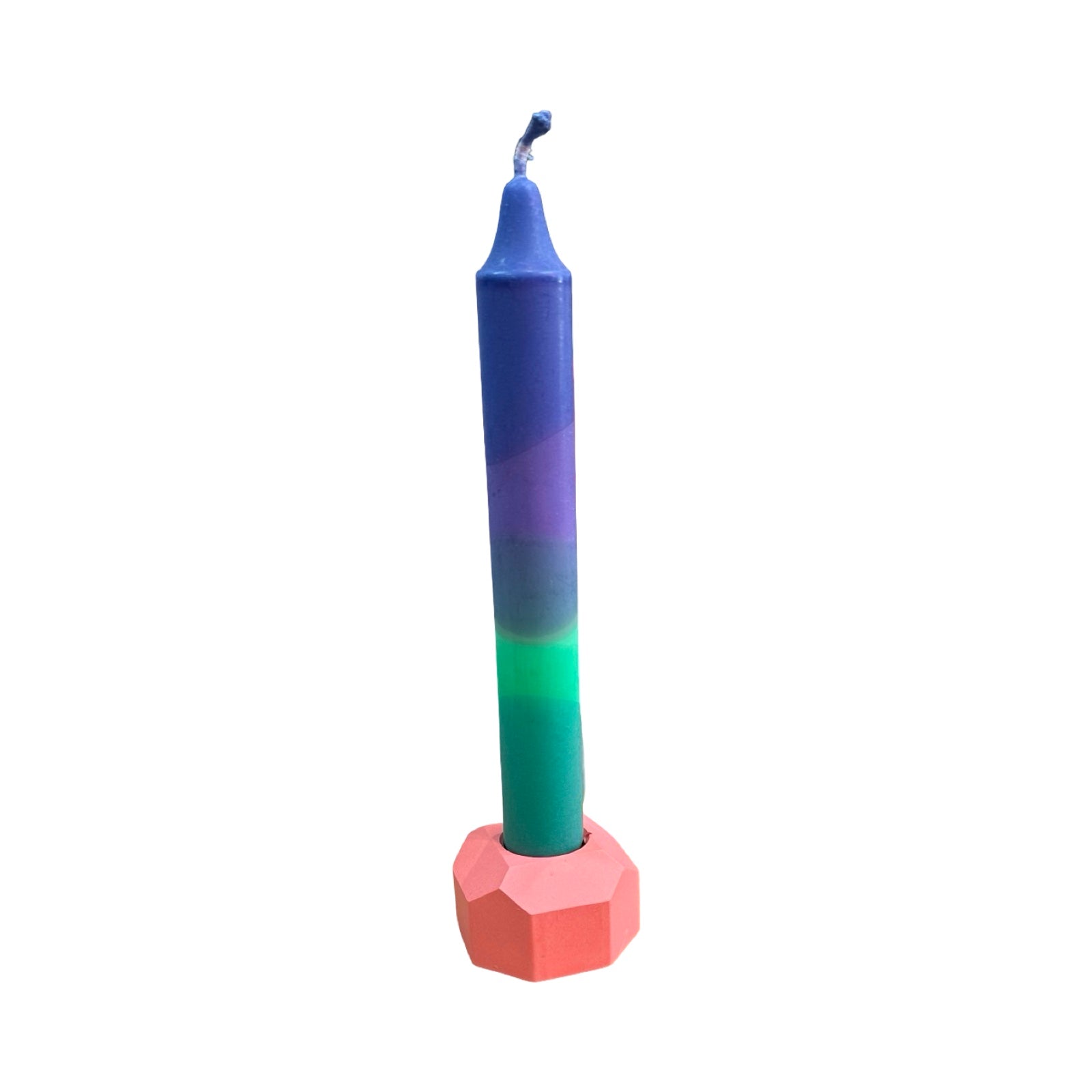 A small geometric shaped dinner candle holder in pink holding a blue, purple and green dinner candle.