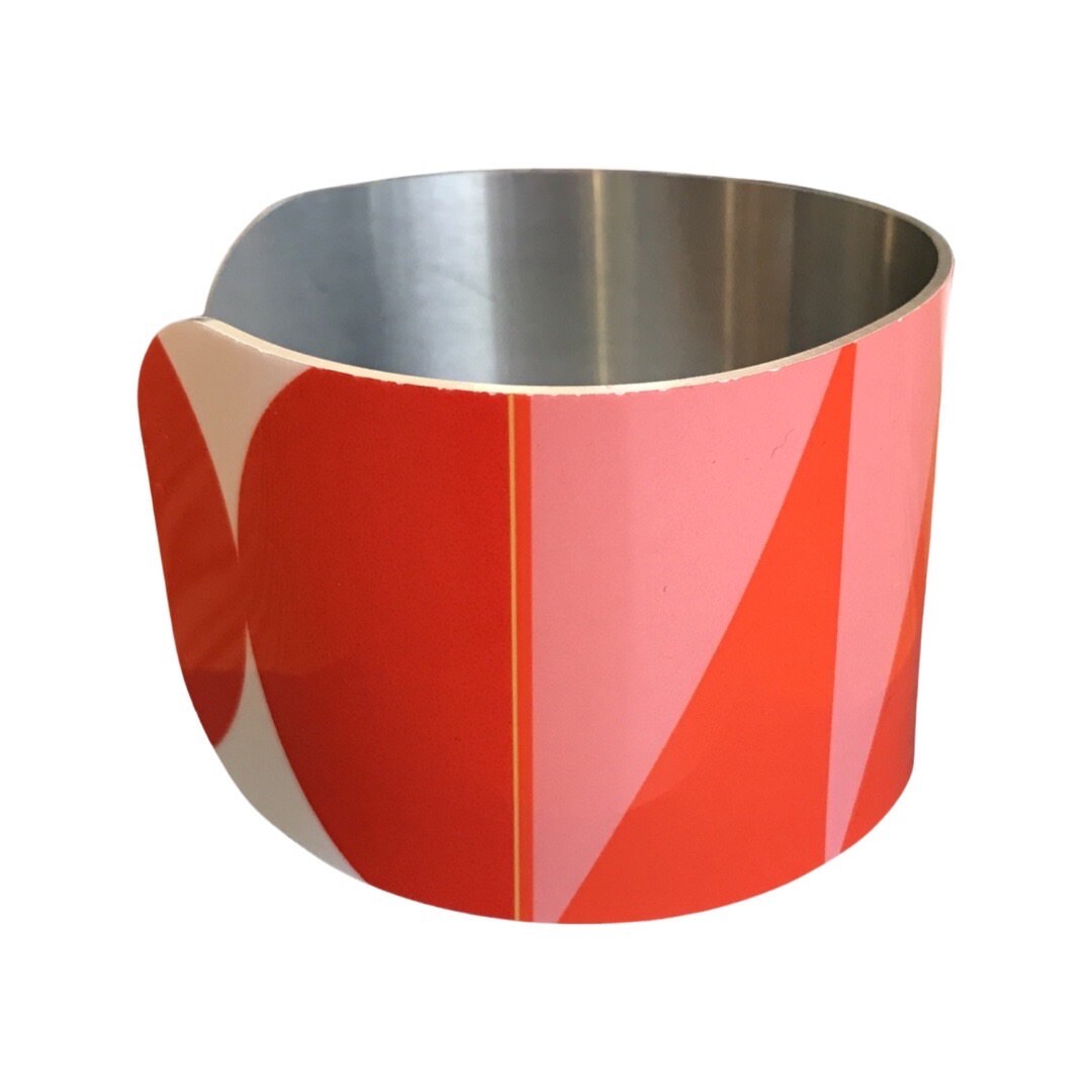 Right side of a narrow cuff bracelet featuring a geometric multicoloured design.