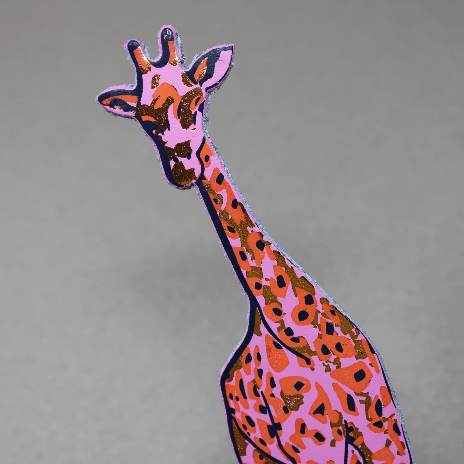 Colourful giraffe bookmark on a grey background.