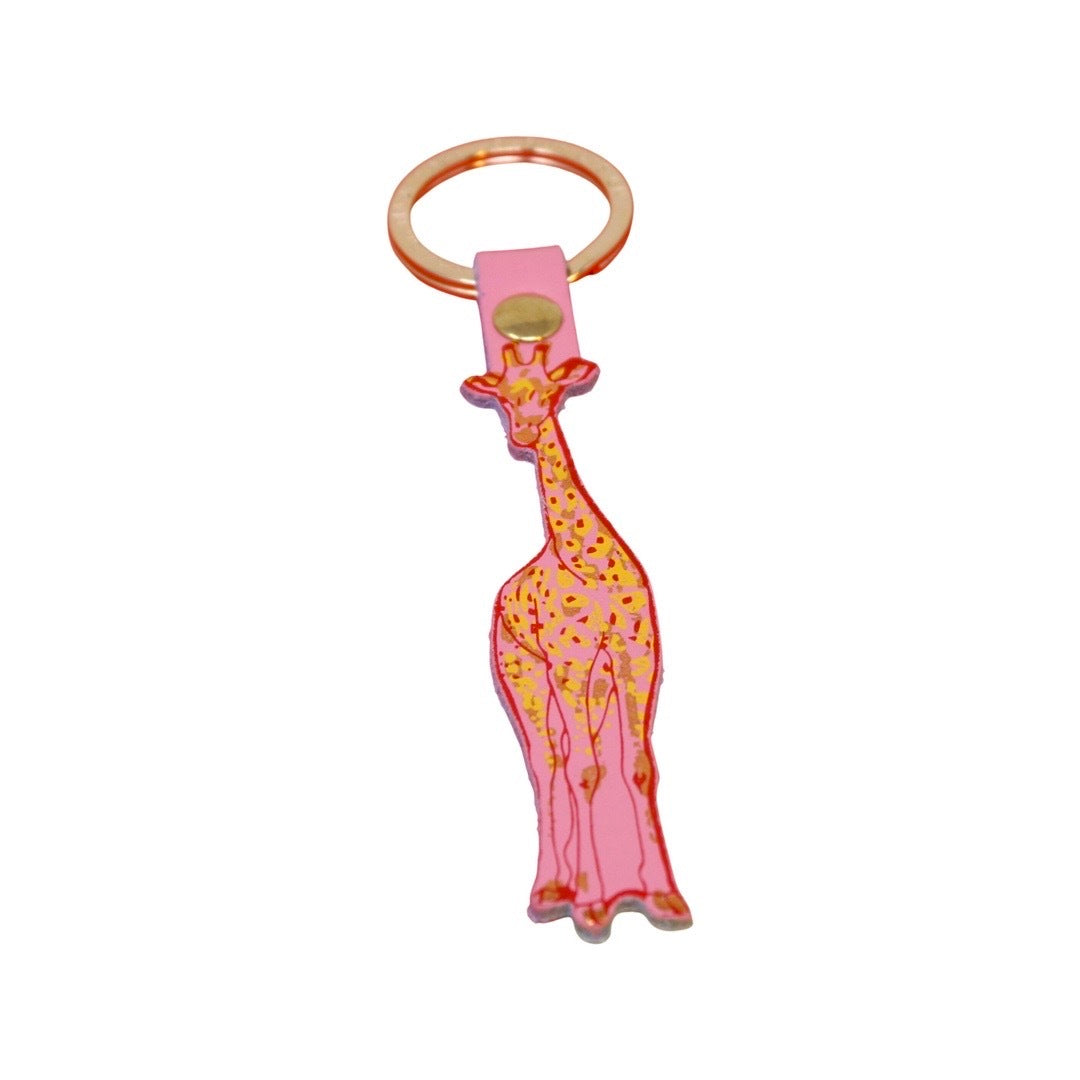 A pink giraffe-shaped leather keyring with a red outline and yellow and gold embossed detail and a gold ring.