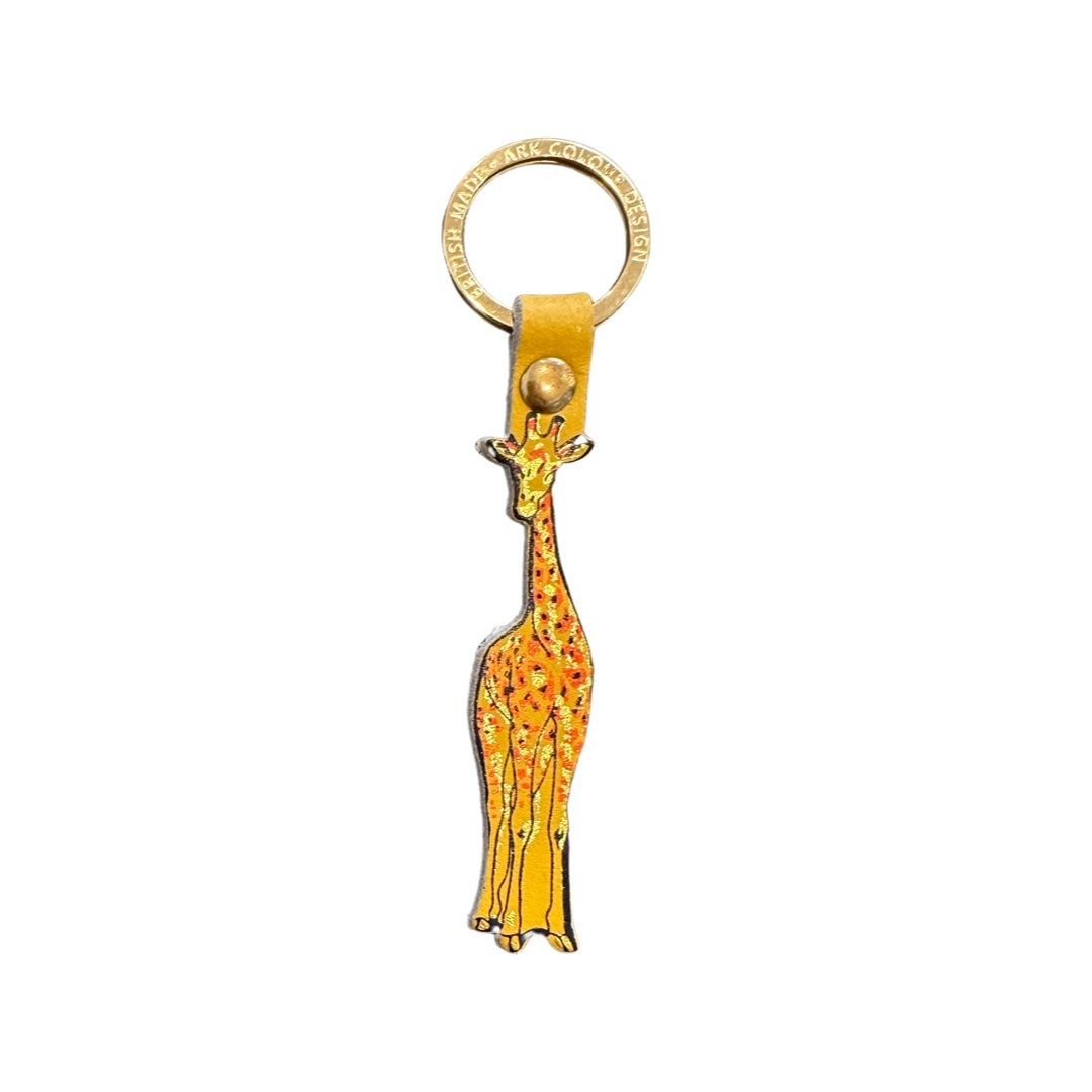 A yellow giraffe-shaped leather keyring with a black outline and orange and gold embossed detail and a gold ring.