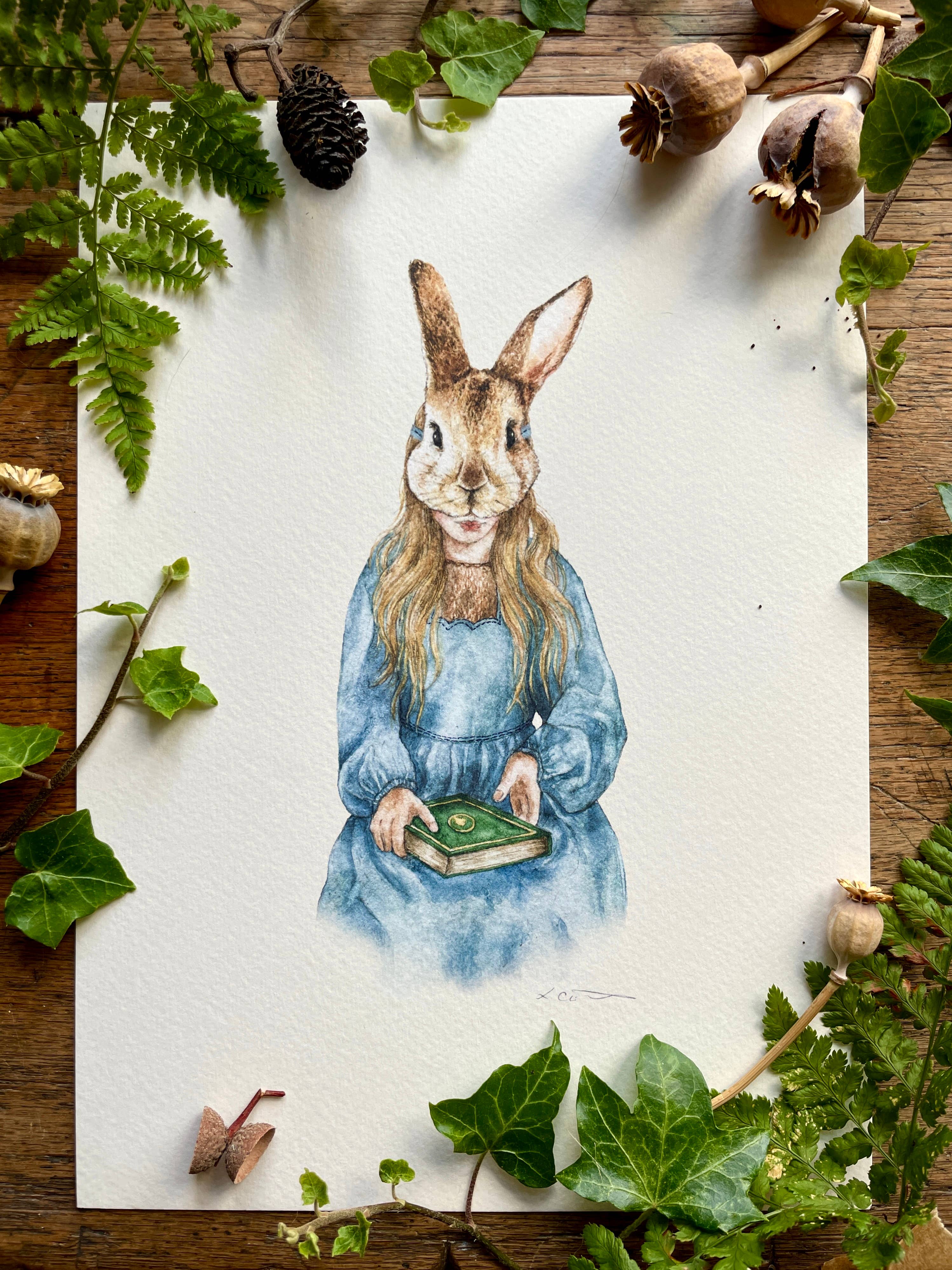 An art print of a girl wearing a rabbit mask, dressed in a long blue dress with a lace neckline, holding a book.