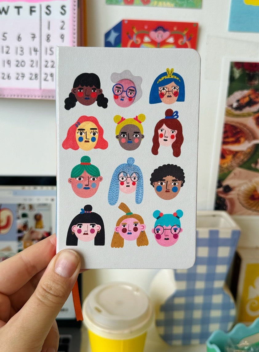 Card with cartoon women held by a hand against a colourful background.
