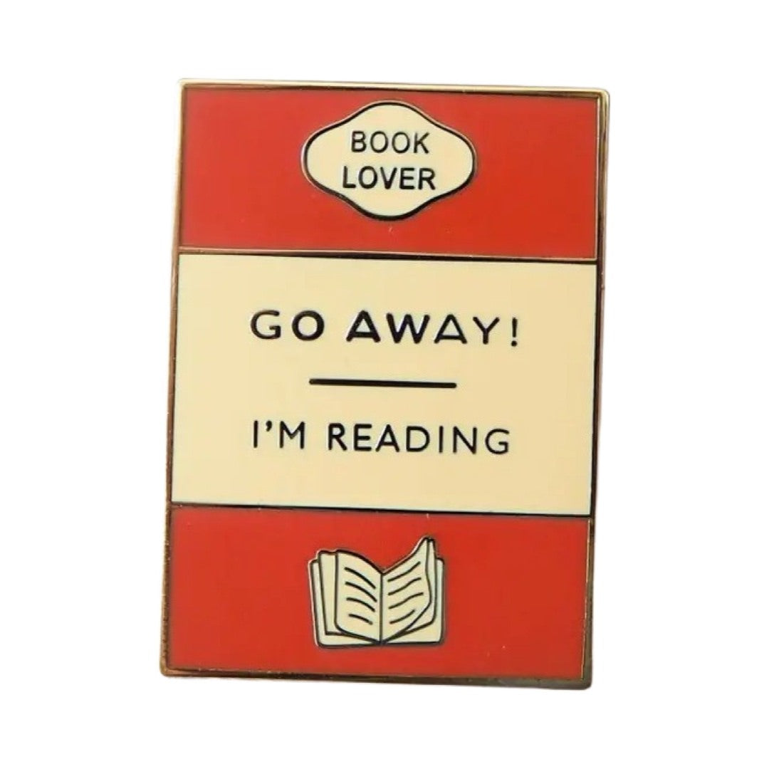 Rectangular enamel pin badge designed as a book cover in orange, gold and cream with the text 'Go Away! I'm Reading' in the centre. 