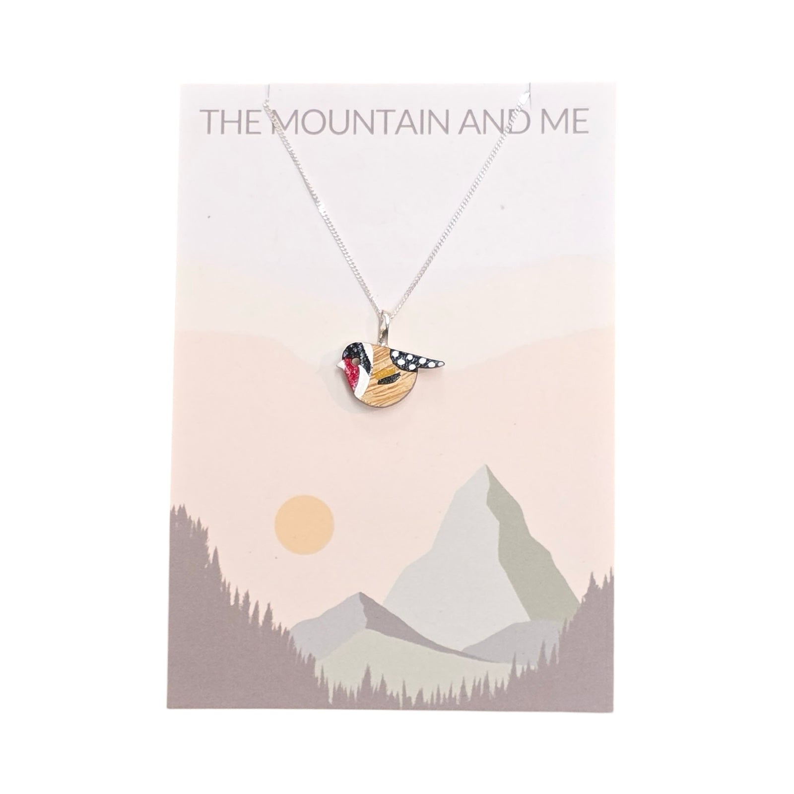 A bird-shaped red and black goldfinch painted pendant with a sterling silver chain on a branded backing card.