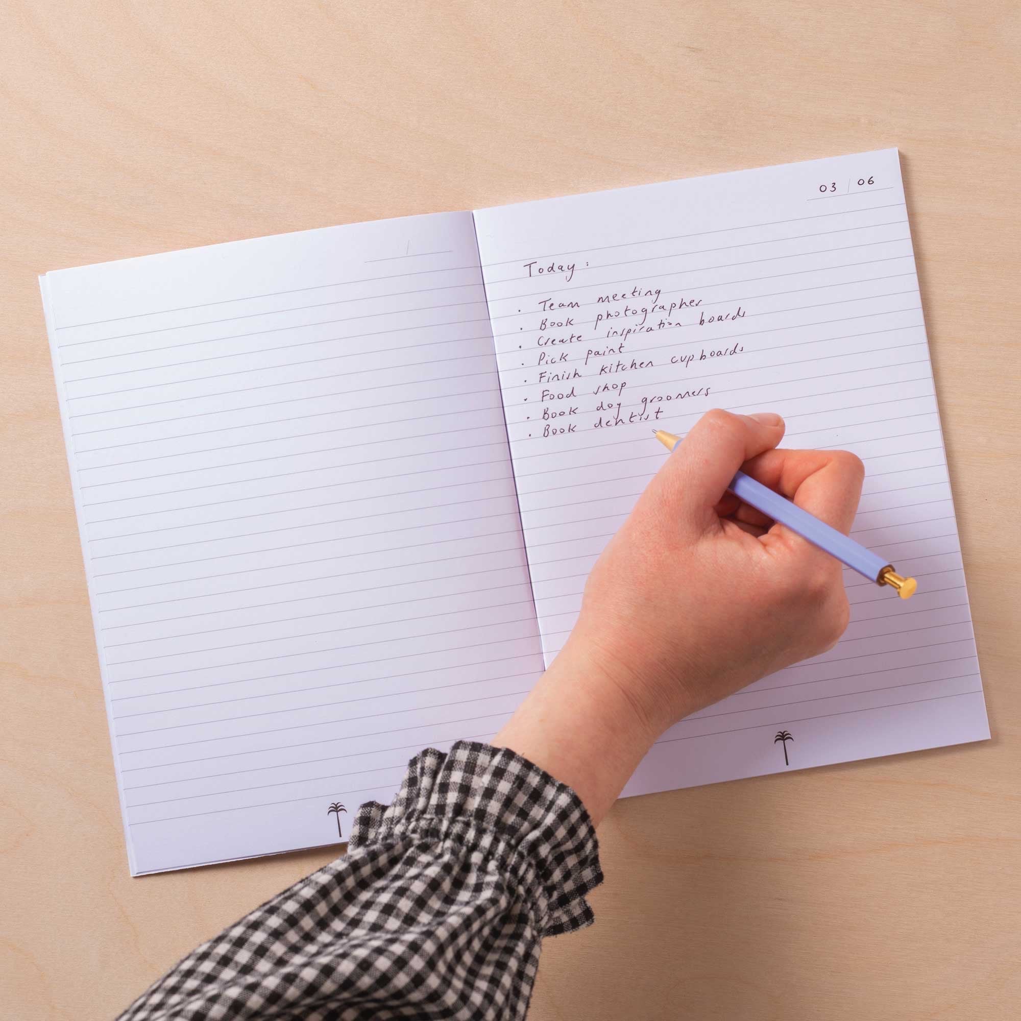 Hand writing in a notebook with a pen on a beige background.