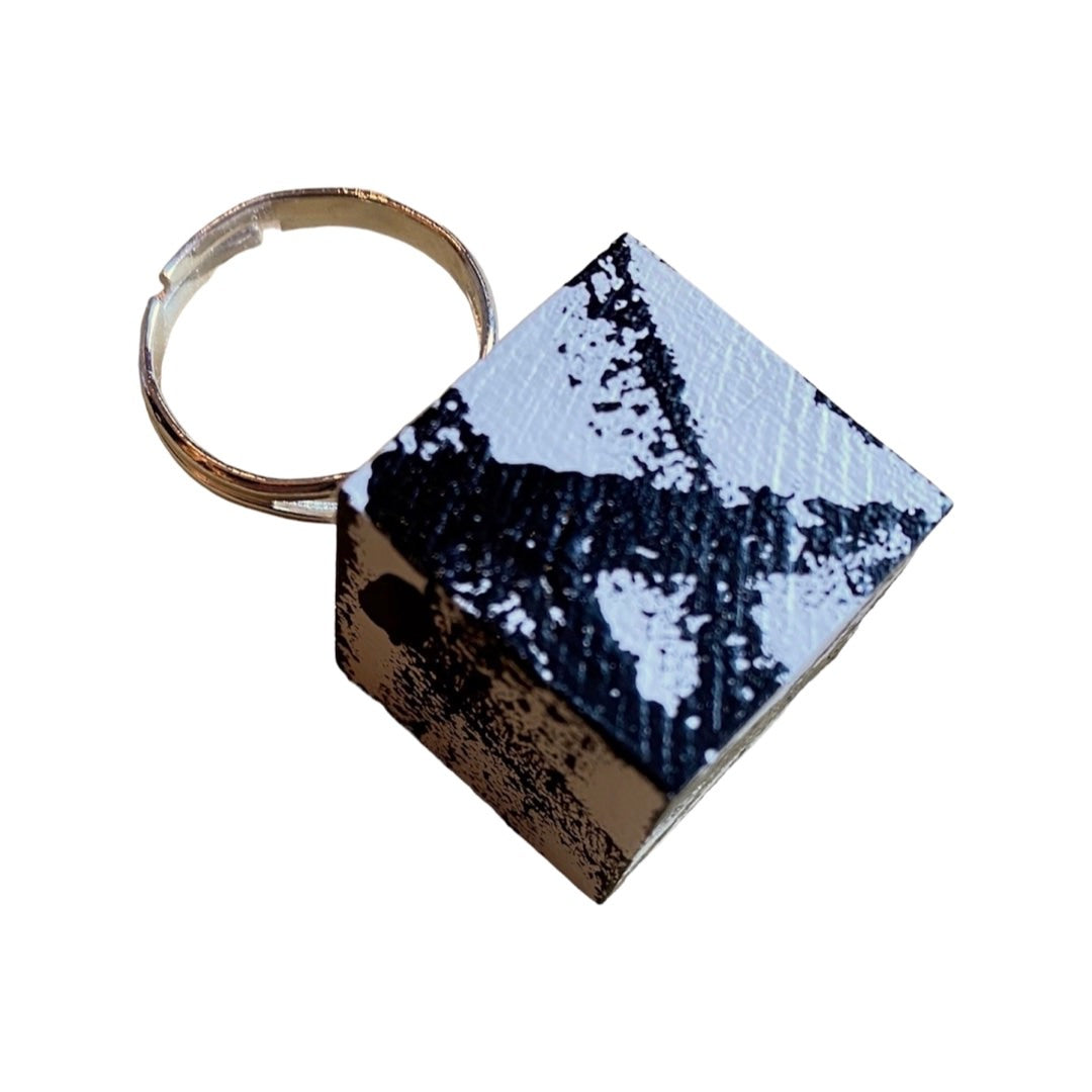 A black and white hand painted wooden cube ring with a graffiti design, set on an adjustable silver plated ring.
