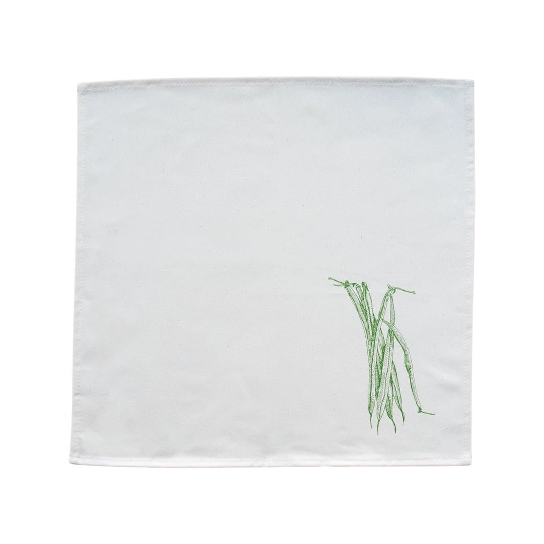 Cream cotton napkin with screen printed green beans rolled on a plate.