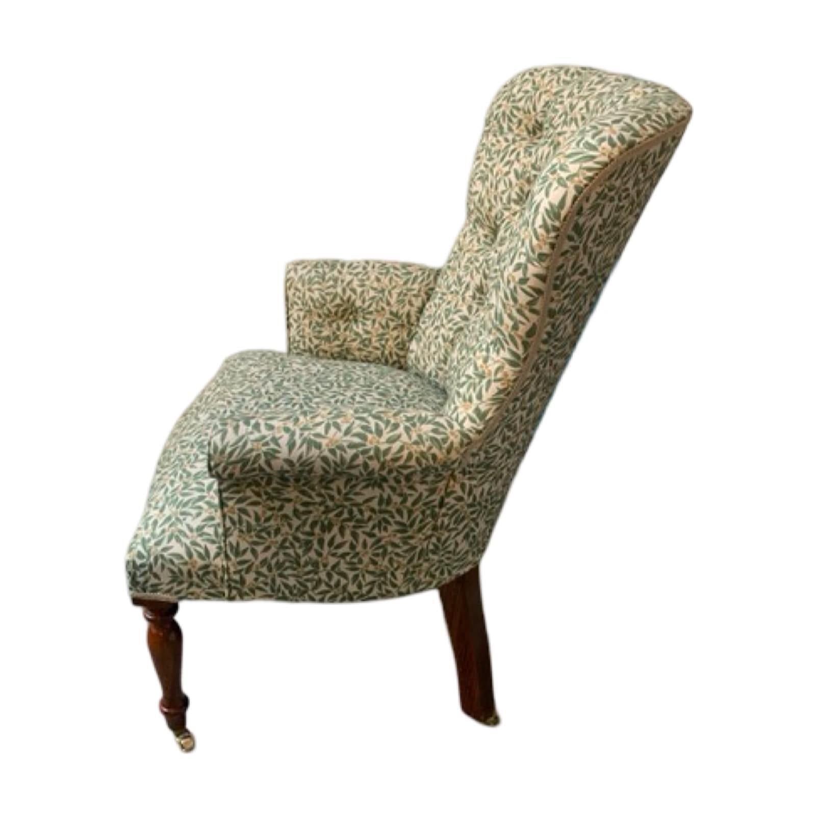 A hand-crafted occasional armchair in a cream line fabric with green foliage and cream-coloured berries. 