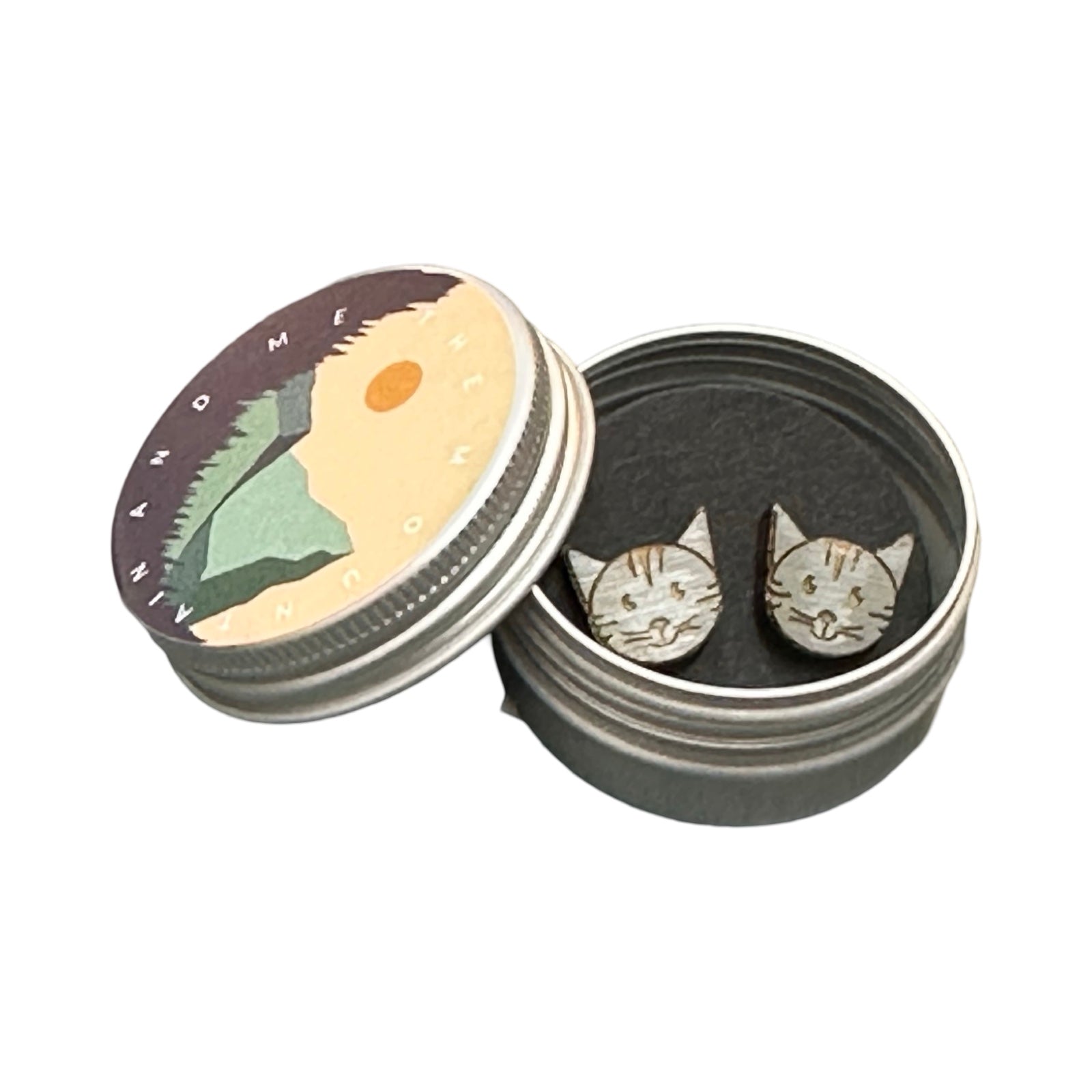 Grey cat head-shaped wooden stud earrings in a small metal tin.