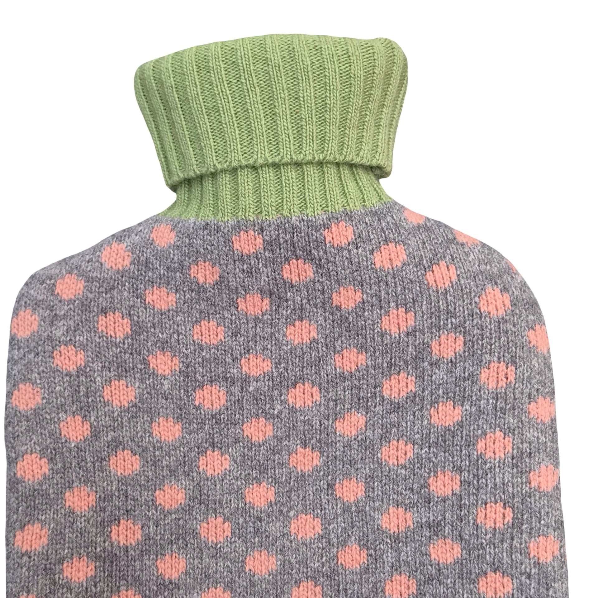 A close-up of a knit turtleneck hot water bottle, featuring a heather grey body with pink polka dots and a light sage green ribbed turtleneck collar.