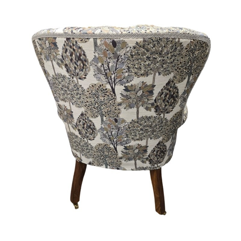 A hand-crafted occasional armchair covered in digitally printed cream cotton/linen blend fabric with a grey and beige tree design. 