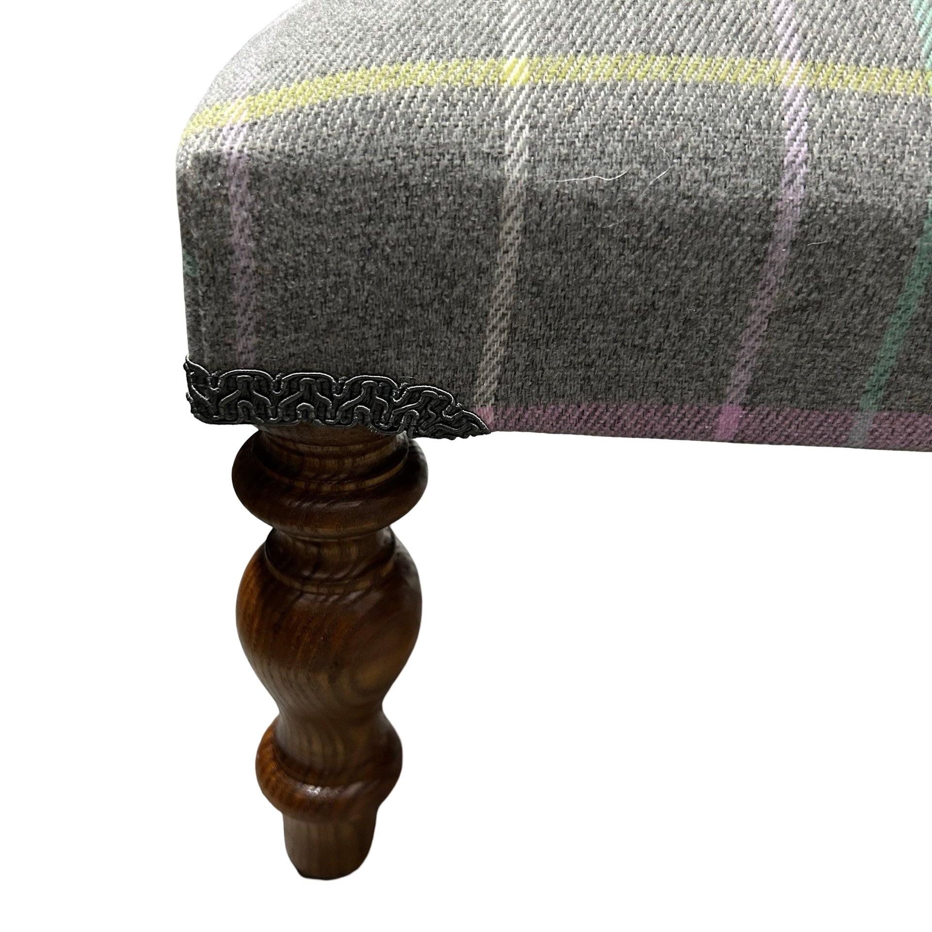 A hand crafted footstool covered in grey cotton fabric which has windowpane check stripes in pink, white, aqua and yellow fabric with mahogany stained legs.