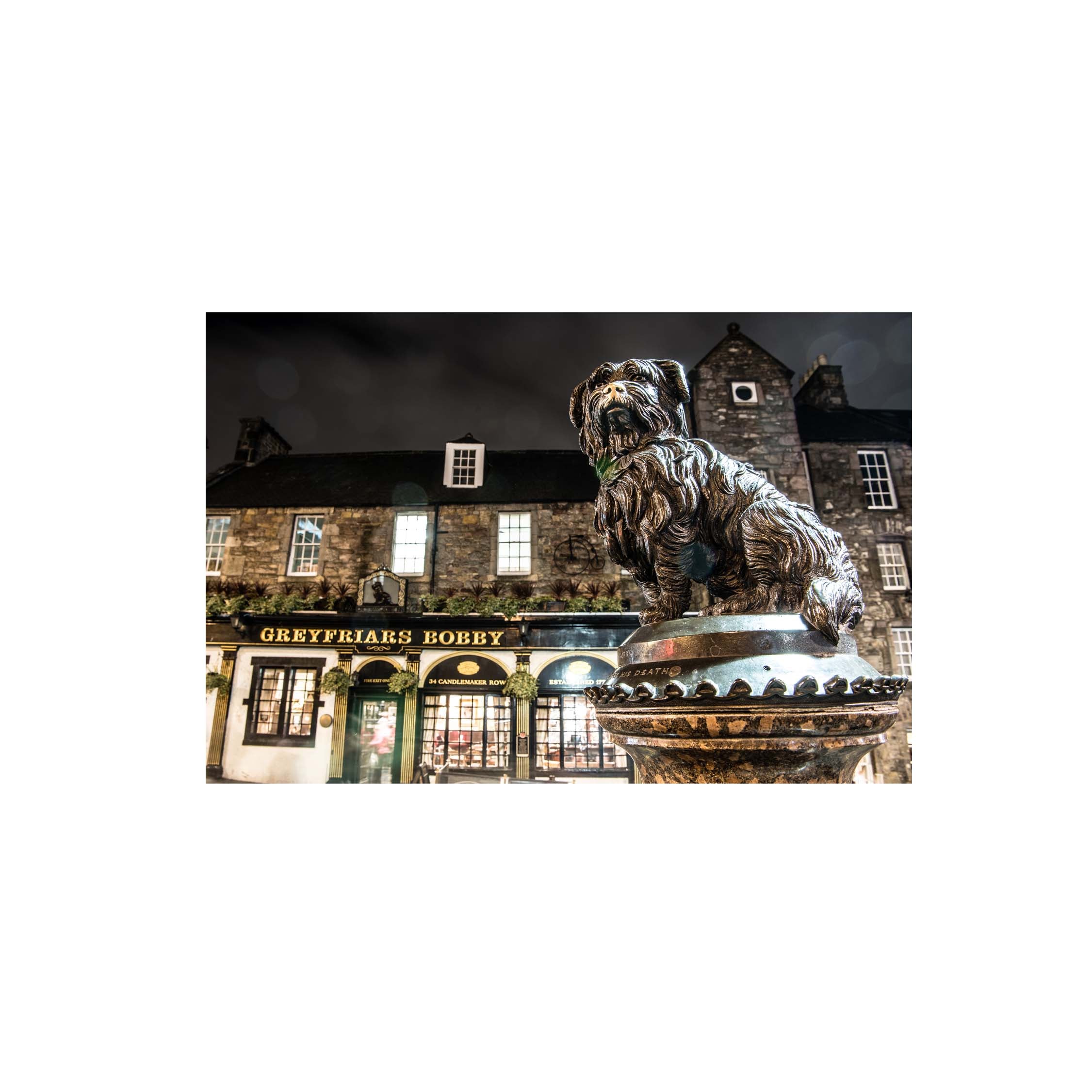 A photography of the Greyfriars Bobby statue in front of the 'Greyfriars Bobby' pub.