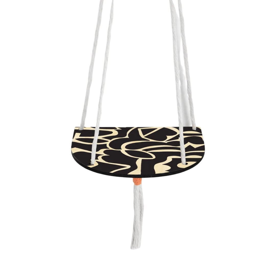 A black and natural wood shelf hanging on 4 strings of rope that sits against the wall.