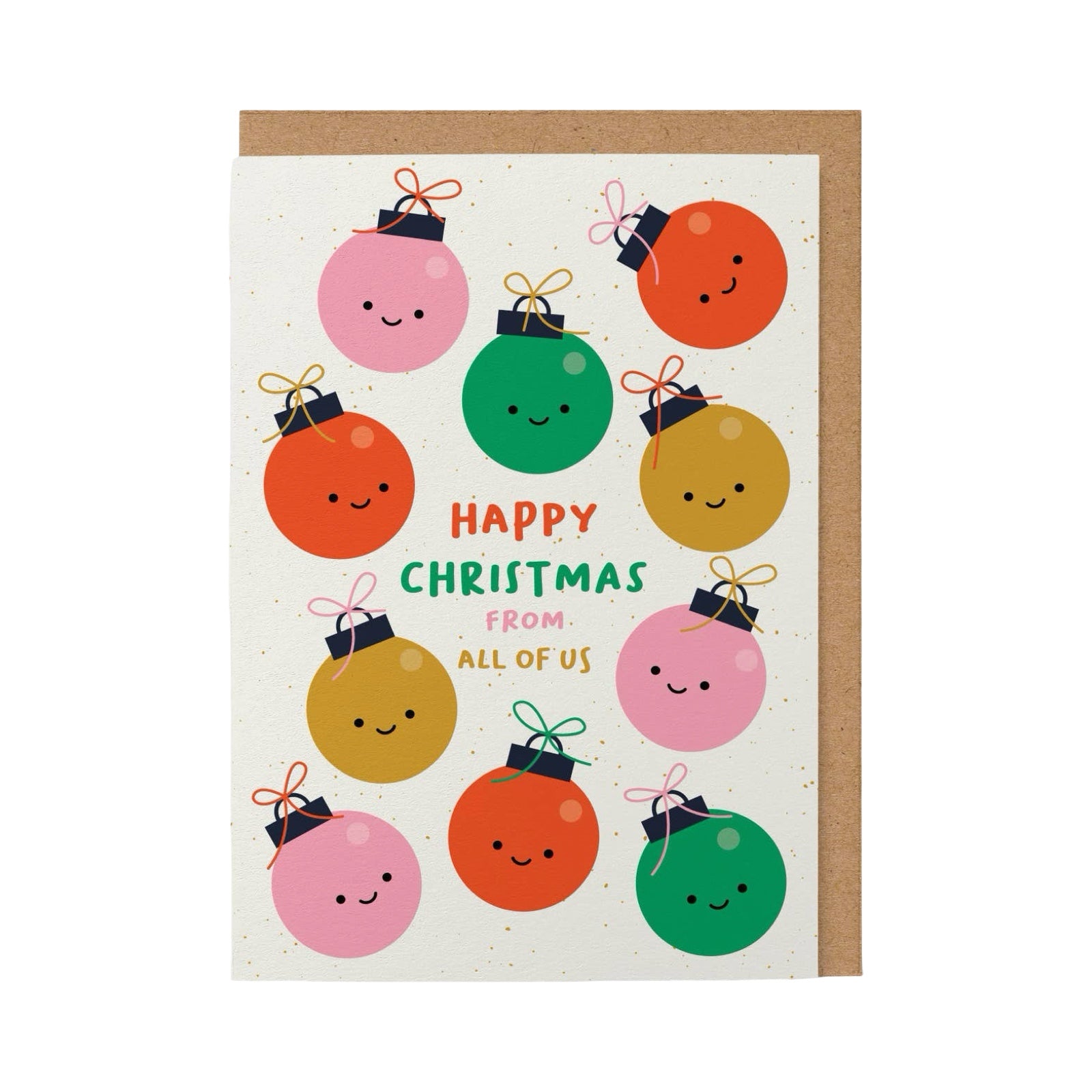 A Christmas greeting card with a kraft envelope, featuring cute, smiling cartoon Christmas ornaments in pink, orange, green, and gold around the text 'Happy Christmas from all of us' on a white background with subtle gold speckles.