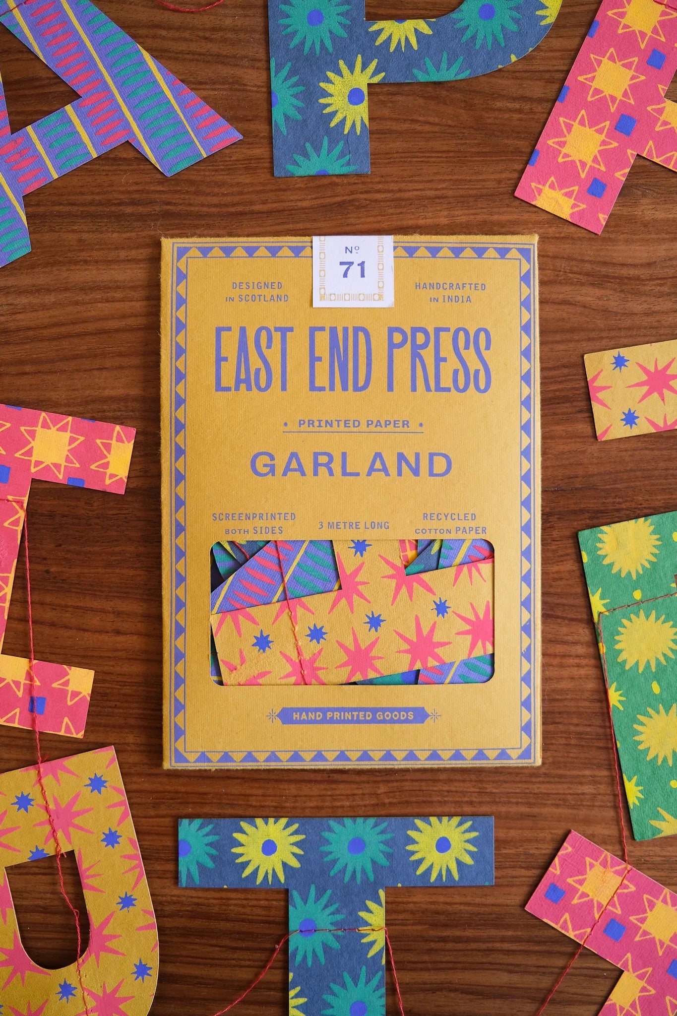 Box of East End Press Garland printed paper with colorful letters on a wooden surface.
