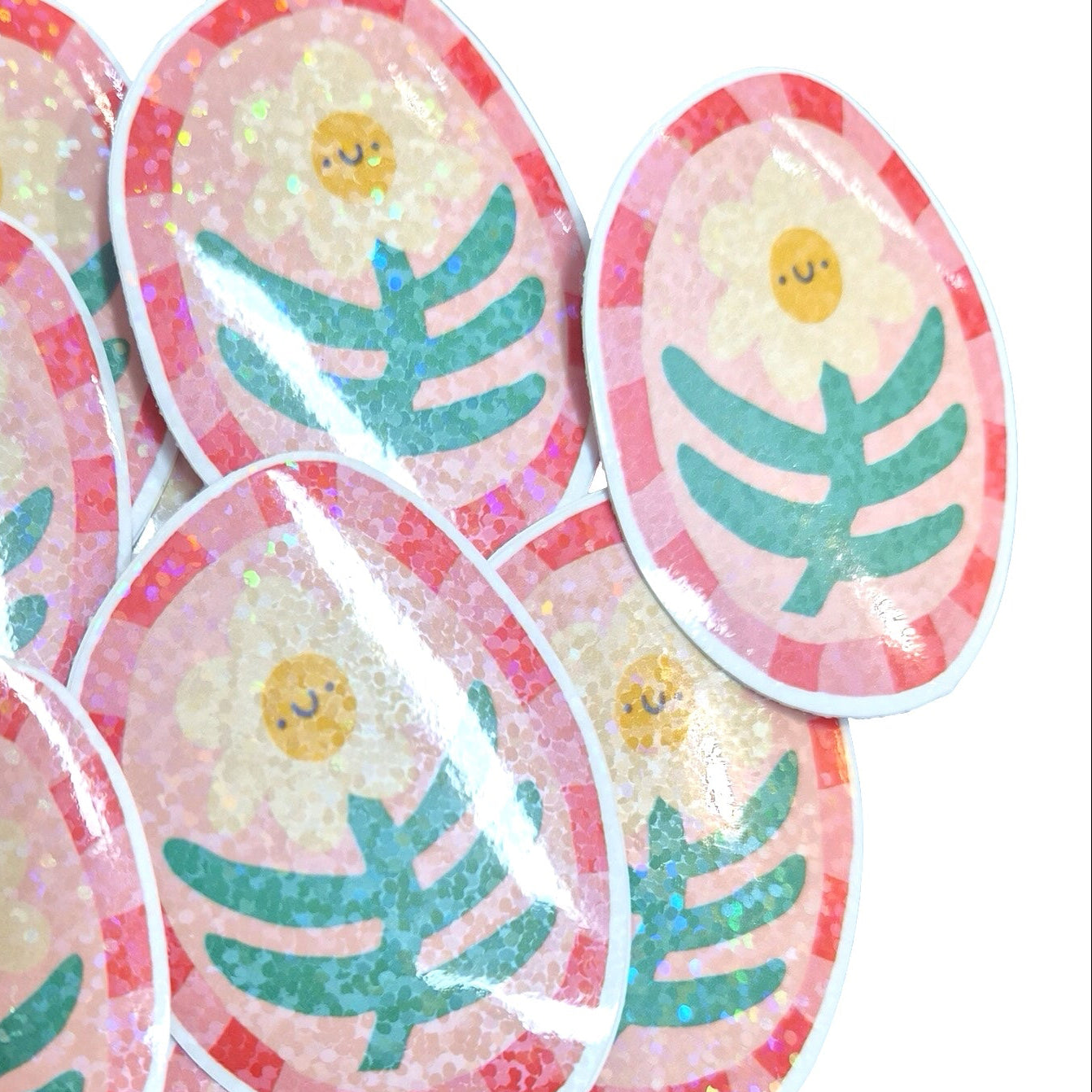 A pile of oval stickers featuring a cute yellow sun face with closed eyes, surrounded by a pink glittery border and a green leafy branch design on a white background.