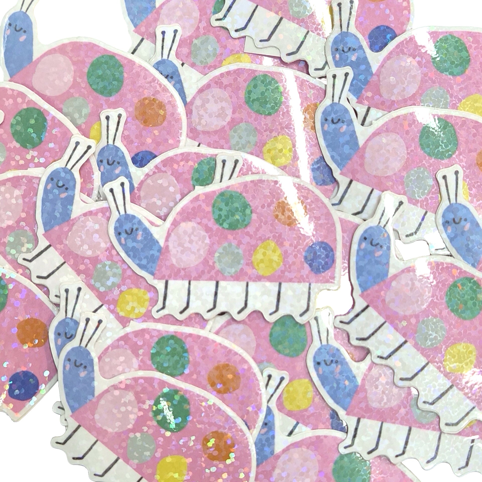A pile of cute die-cut stickers featuring pink glittery snail shells with colourful polka dots and blue snails peeking out, on a white background.
