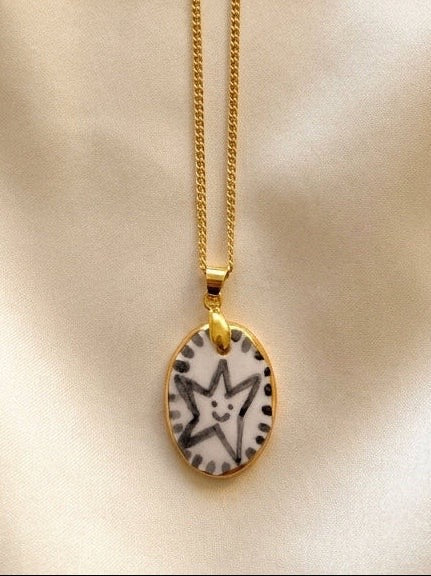 Gold necklace with a pendant featuring a star design on a beige background.