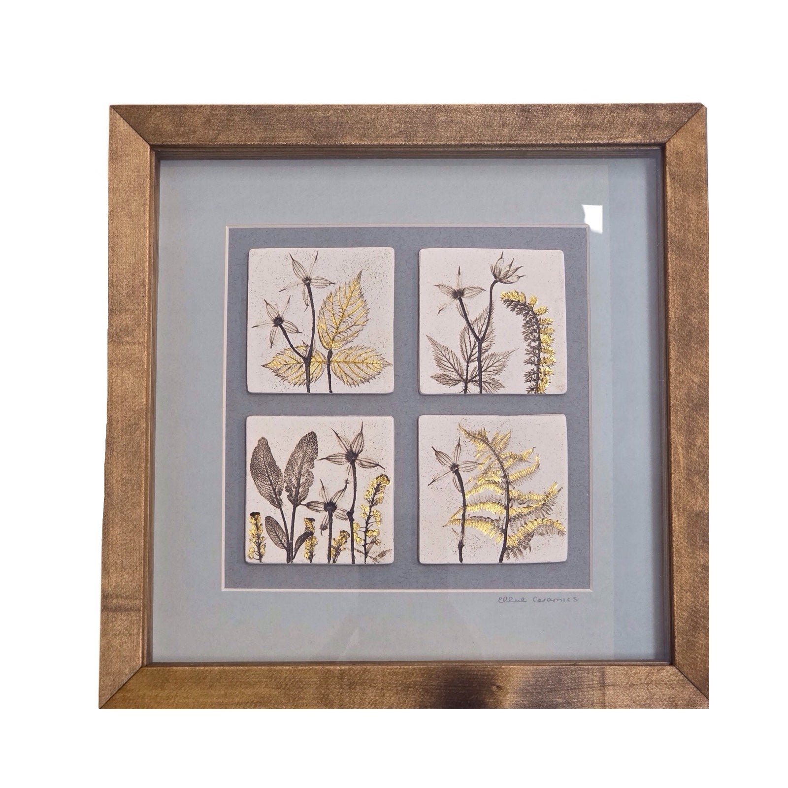 Framed artwork with botanical tiles on a grey background in oak frame with gold leaf detailing. 