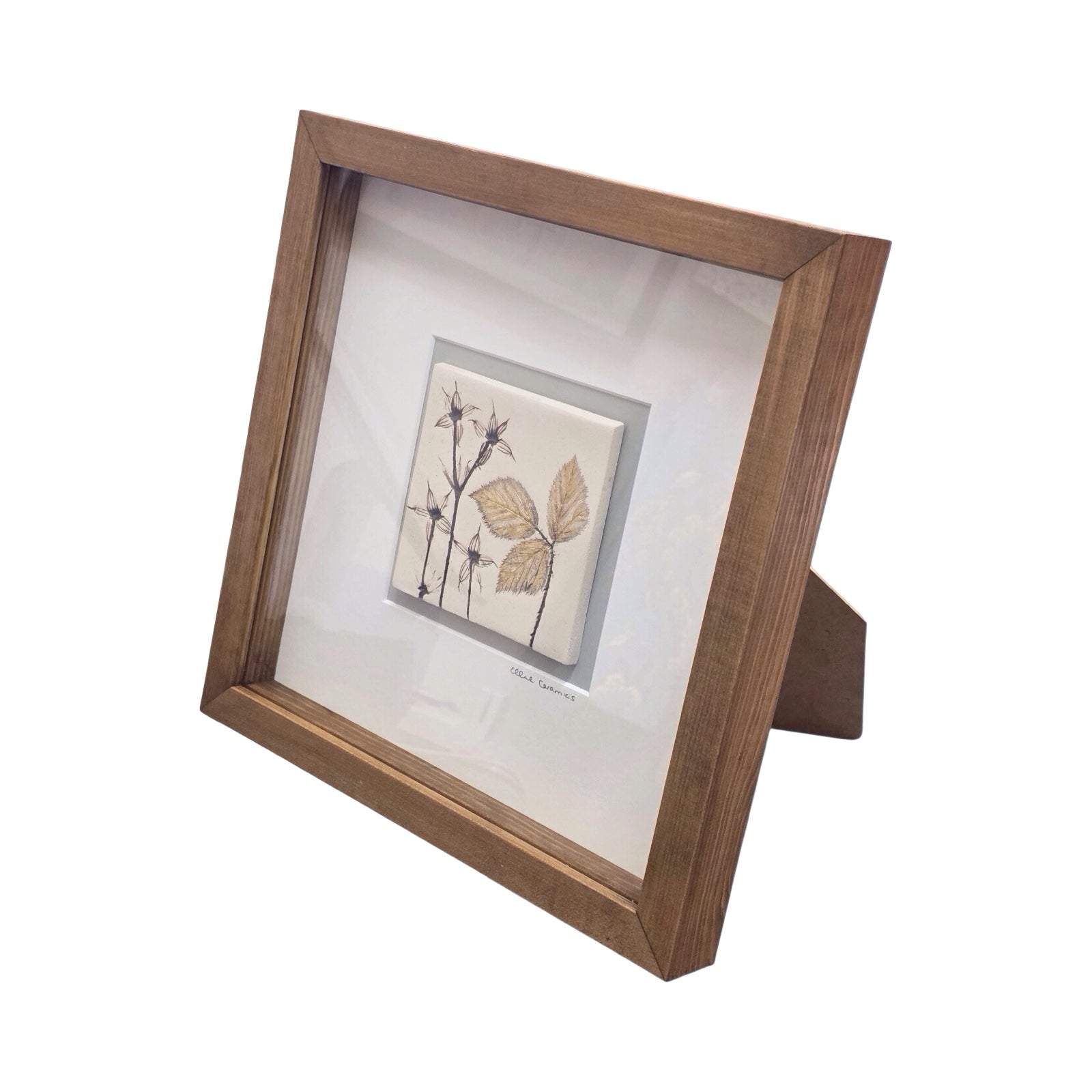 Framed botanical tile featuring hardy geranium in a wooden frame on a white background. 