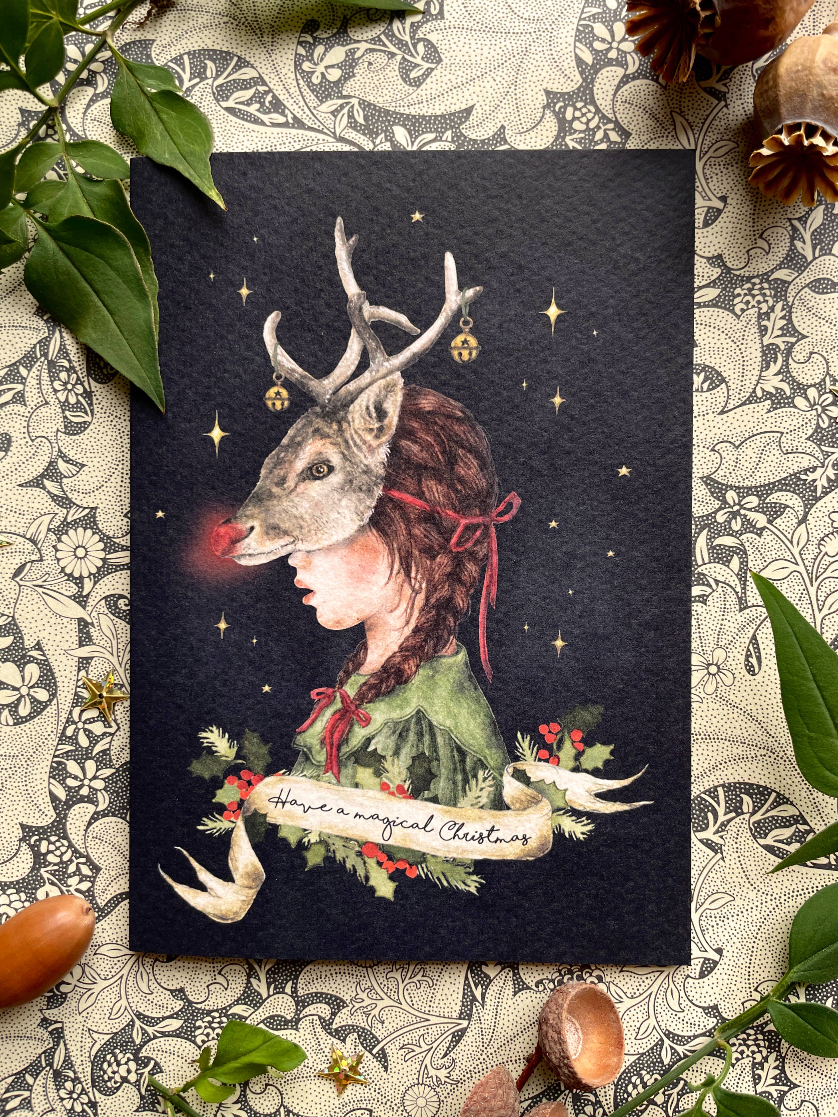 A gorgeous Christmas card of a girl wearing a Rudolph mask, dressed in a green dress. The text 'Have A magical Christmas' is written in a cream banner underneath.