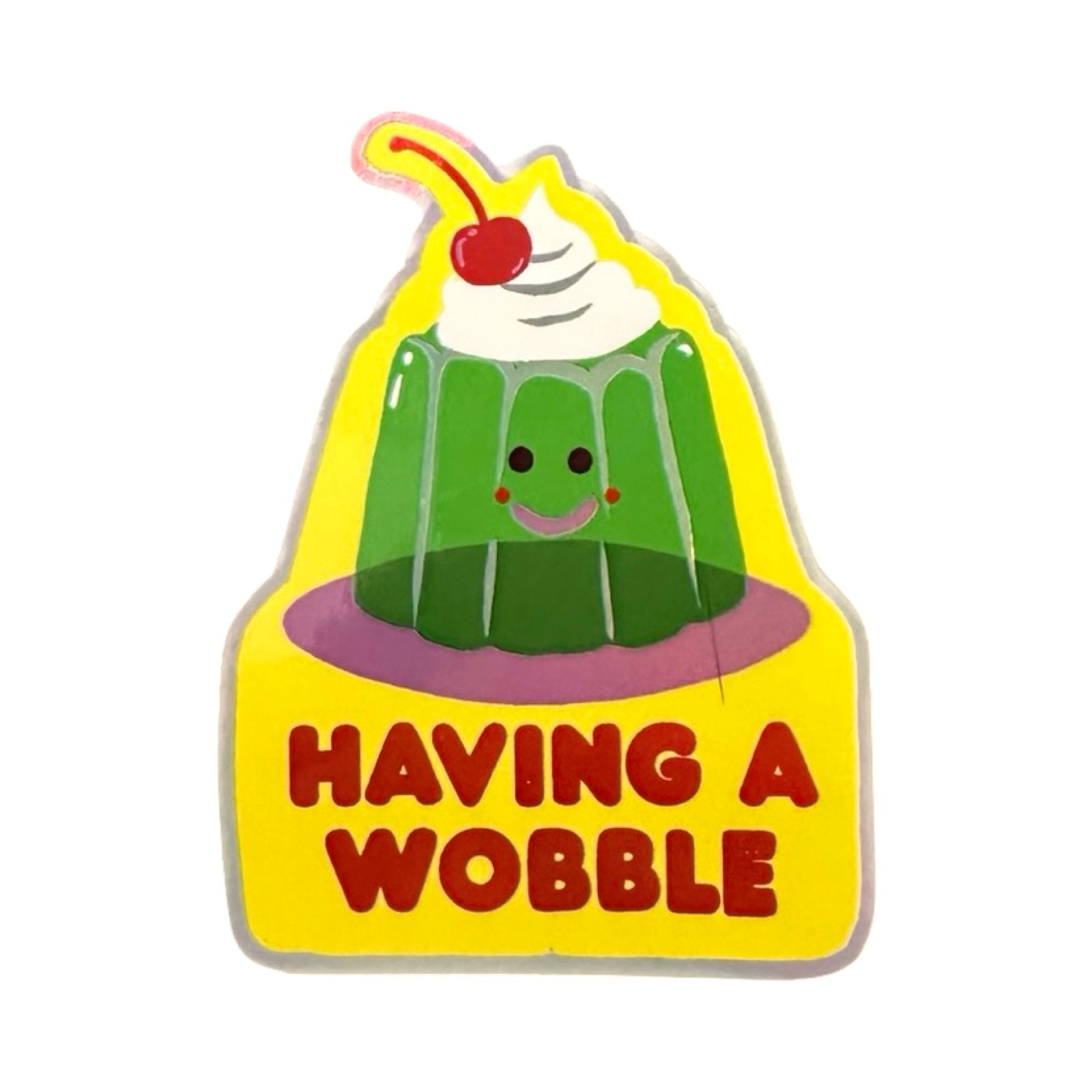 A holographic sticker of a green jelly with a smily face and a cherry on top with the text 'Having A Wobble' underneath.