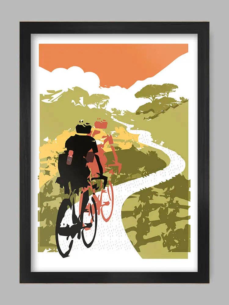 Framed artwork of cyclists on a winding road with a colorful sky.