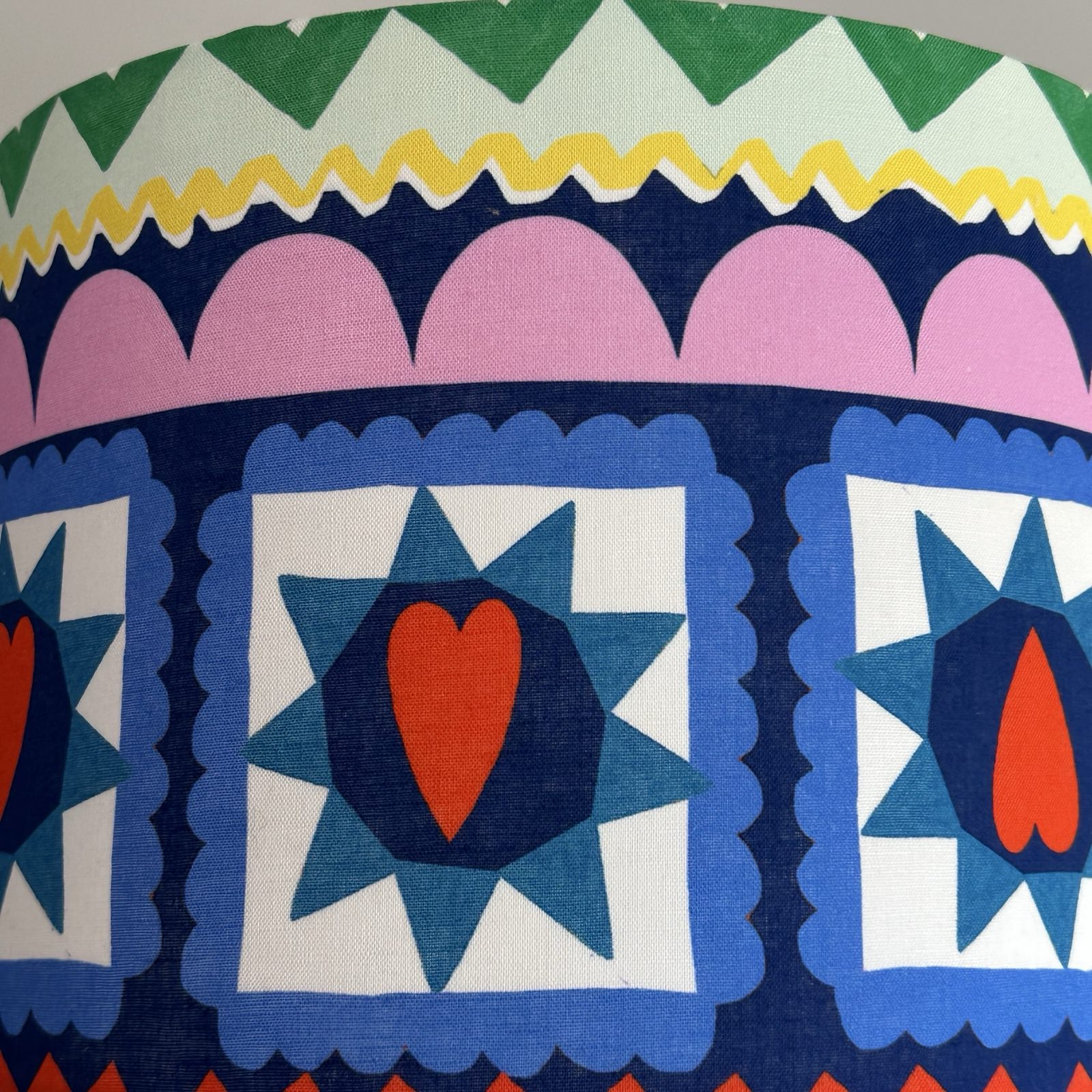 Close-up of a fabric with geometric pattern featuring hearts and stars.