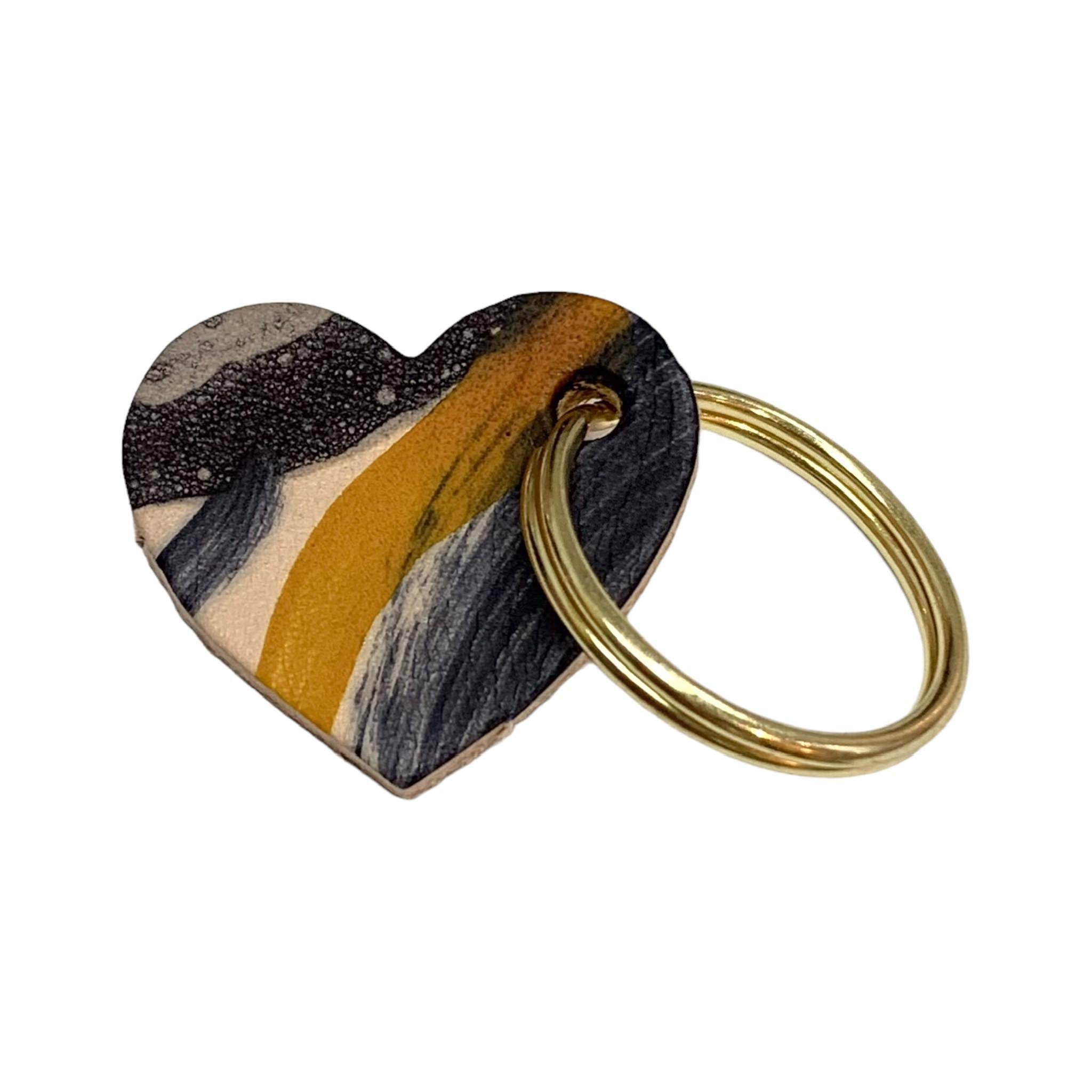 A leather heart-shaped keyring with a brush tone finish and a gold ring.
