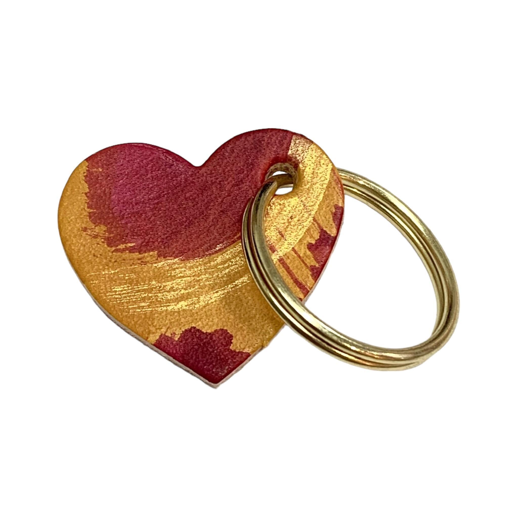 A leather heart-shaped keyring with a brush tone finish and a gold ring.