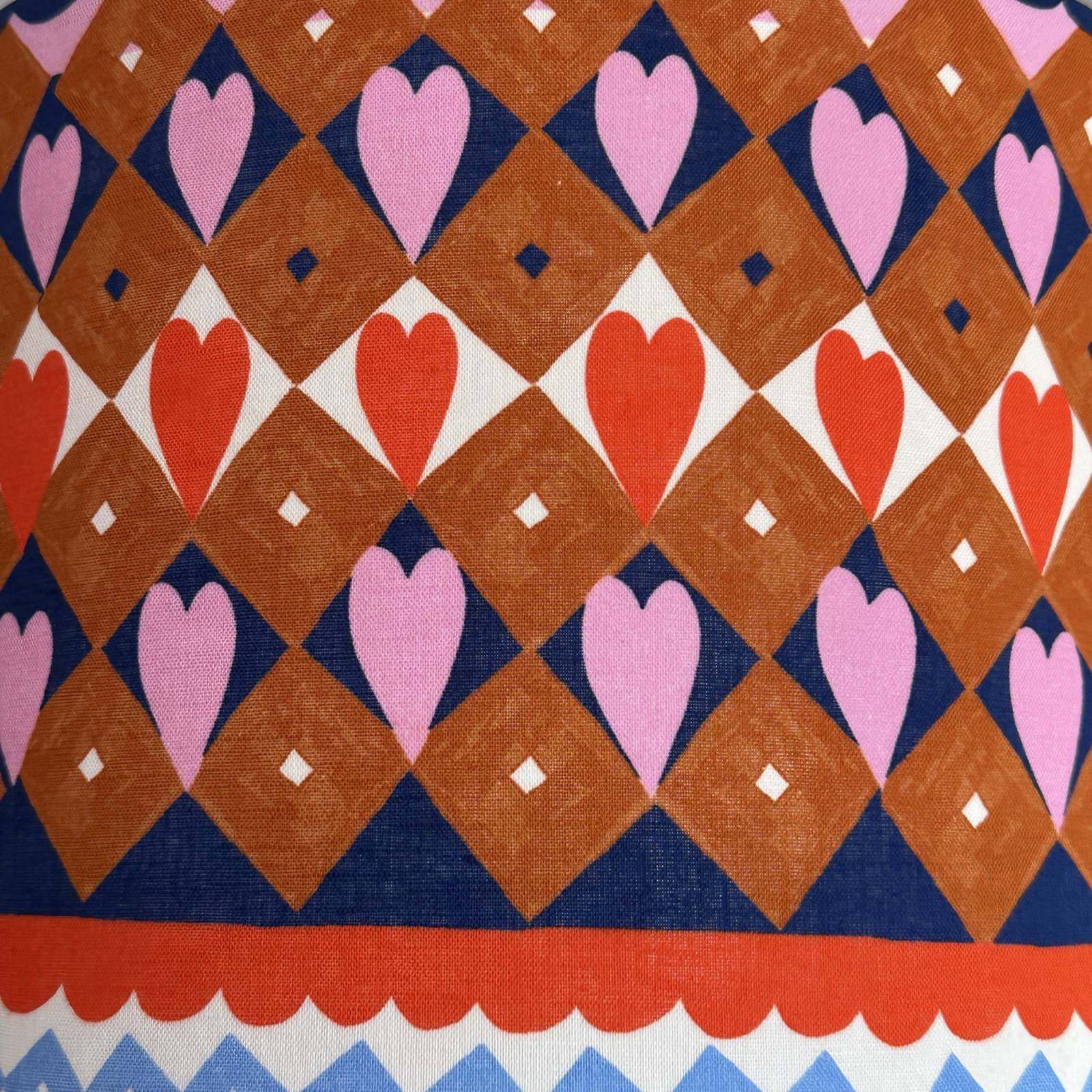 Patterned fabric with hearts and geometric shapes in red, pink, and blue.