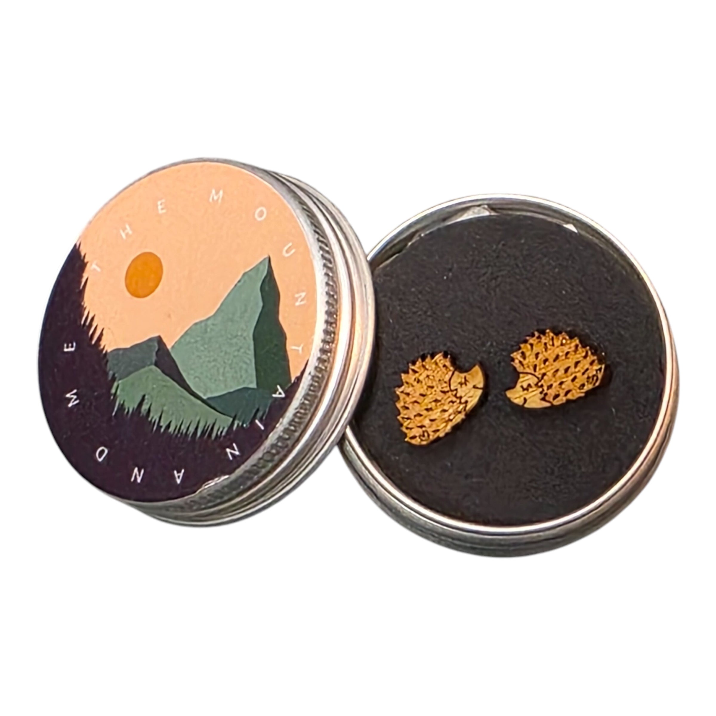 A pair of brown hedgehog-shaped wooden earrings in a small tin.