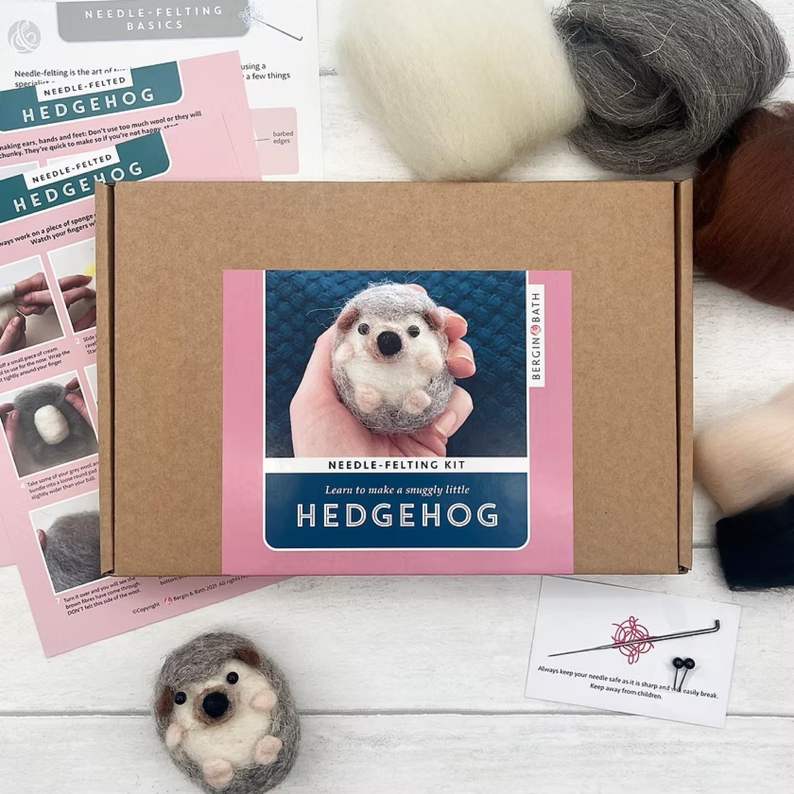Needle felting kit with a hedgehog craft tools and felted hedgehog on a wooden surface.