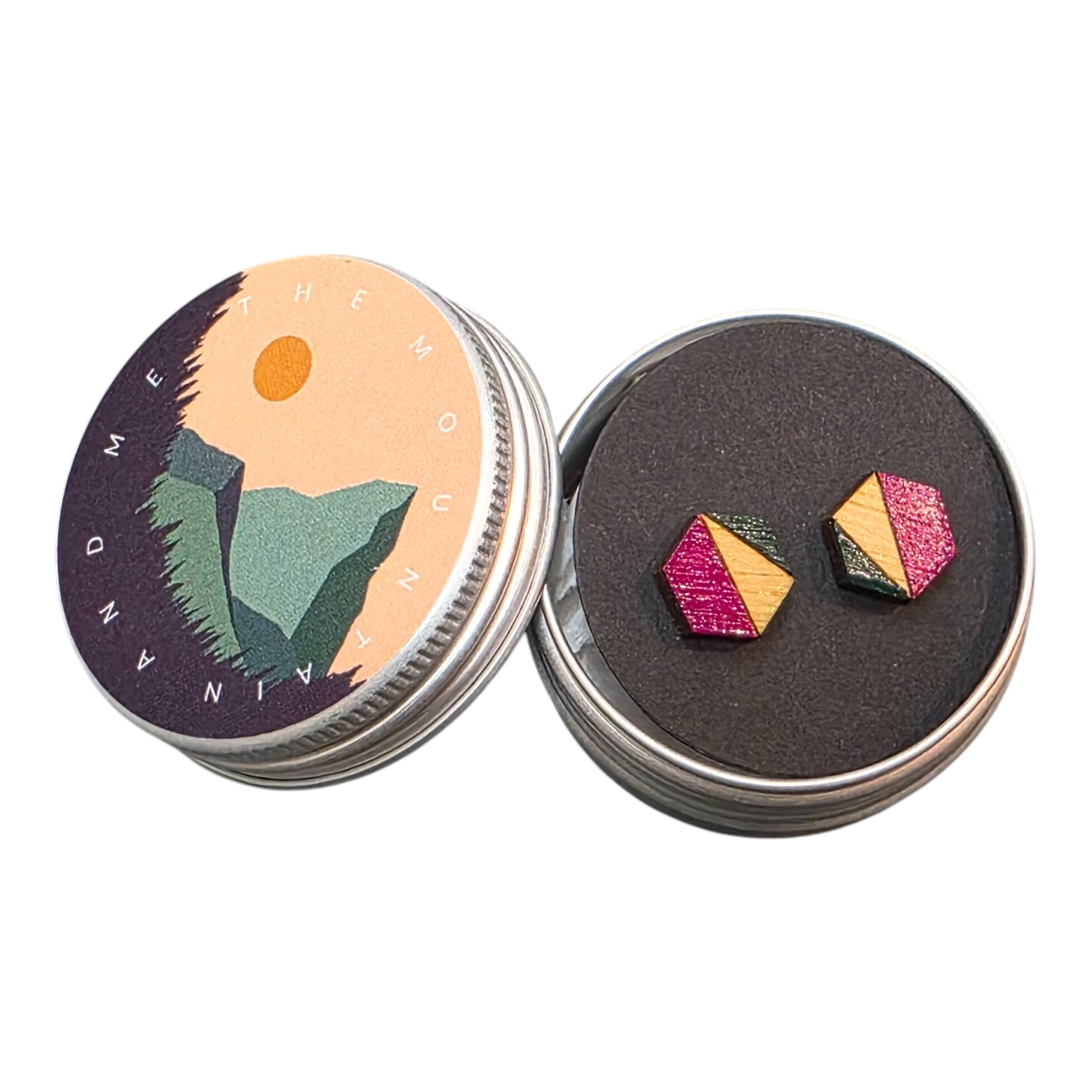 A pair of pink and navy hexagonal bamboo stud earrings in a small metal tin.