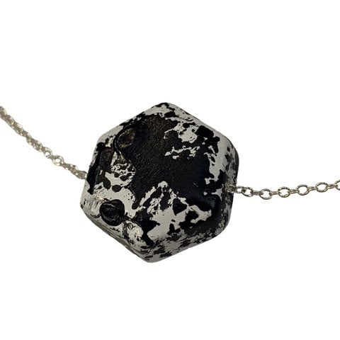A necklace with three hexagon-shaped pendants, featuring a black and white polka dot pattern, displayed against a white background.