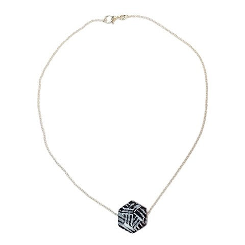 A necklace with three hexagon-shaped pendants, featuring a black and white polka dot pattern, displayed against a white background.