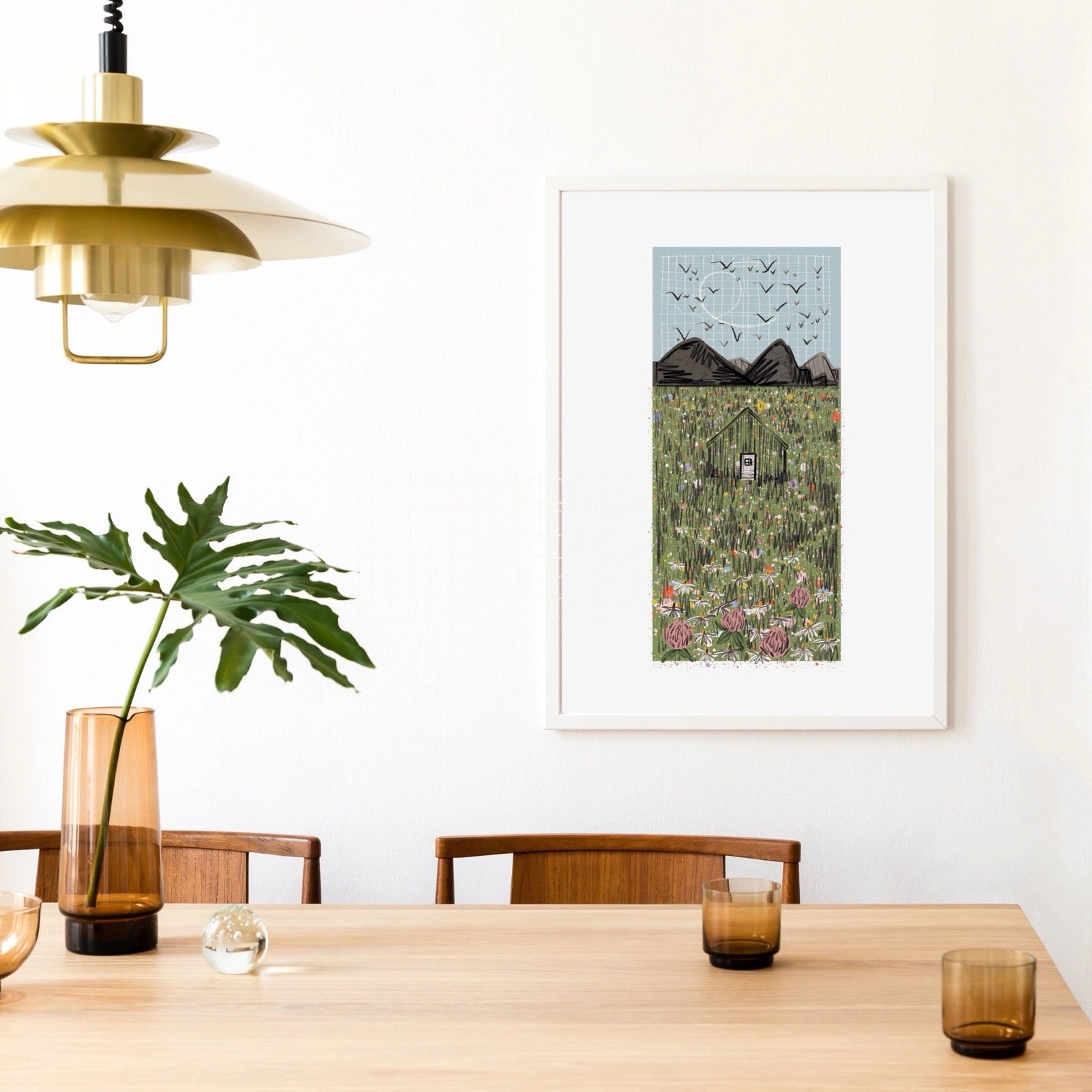Dining room with a wooden table, chairs, a plant, and a framed artwork on the wall.